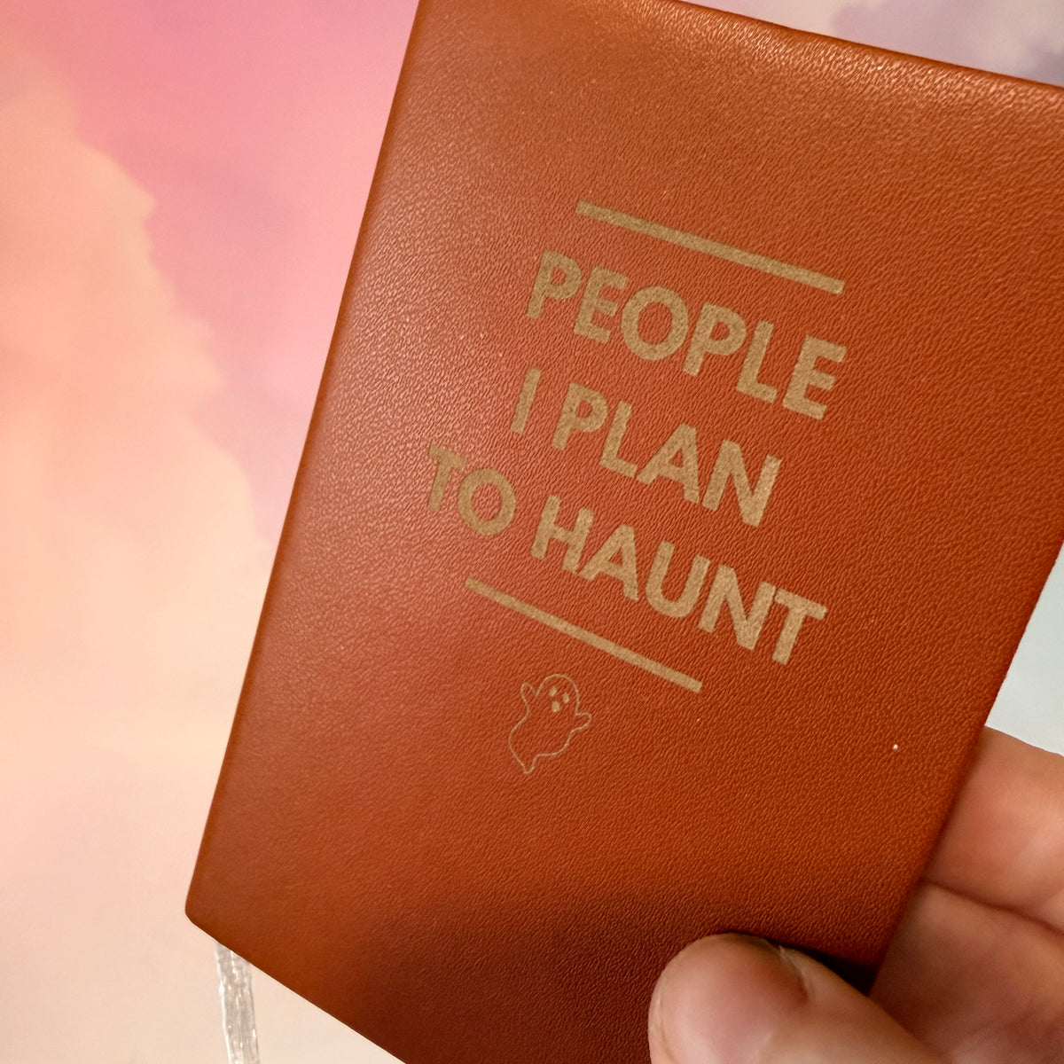 Mini blue notebook with “People I Plan to Haunt” laser engraved in black lettering and a tiny ghost illustration. Approximately 4 x 2.5 inches, with 50 lined pages. Available in brown, green, blue, gray, and black.
