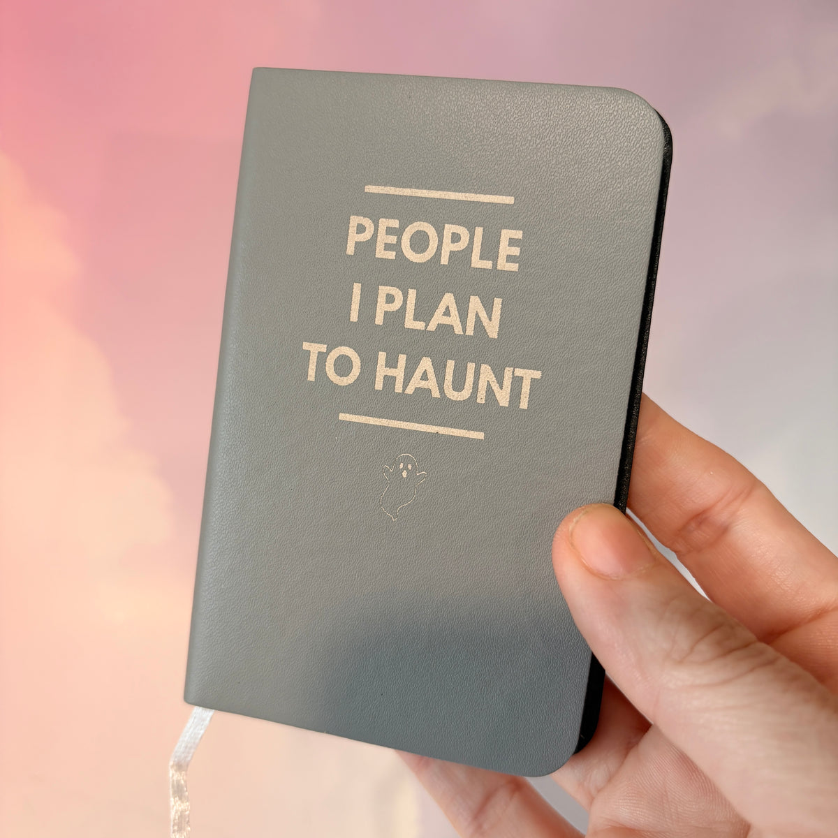 Mini blue notebook with “People I Plan to Haunt” laser engraved in black lettering and a tiny ghost illustration. Approximately 4 x 2.5 inches, with 50 lined pages. Available in brown, green, blue, gray, and black.
