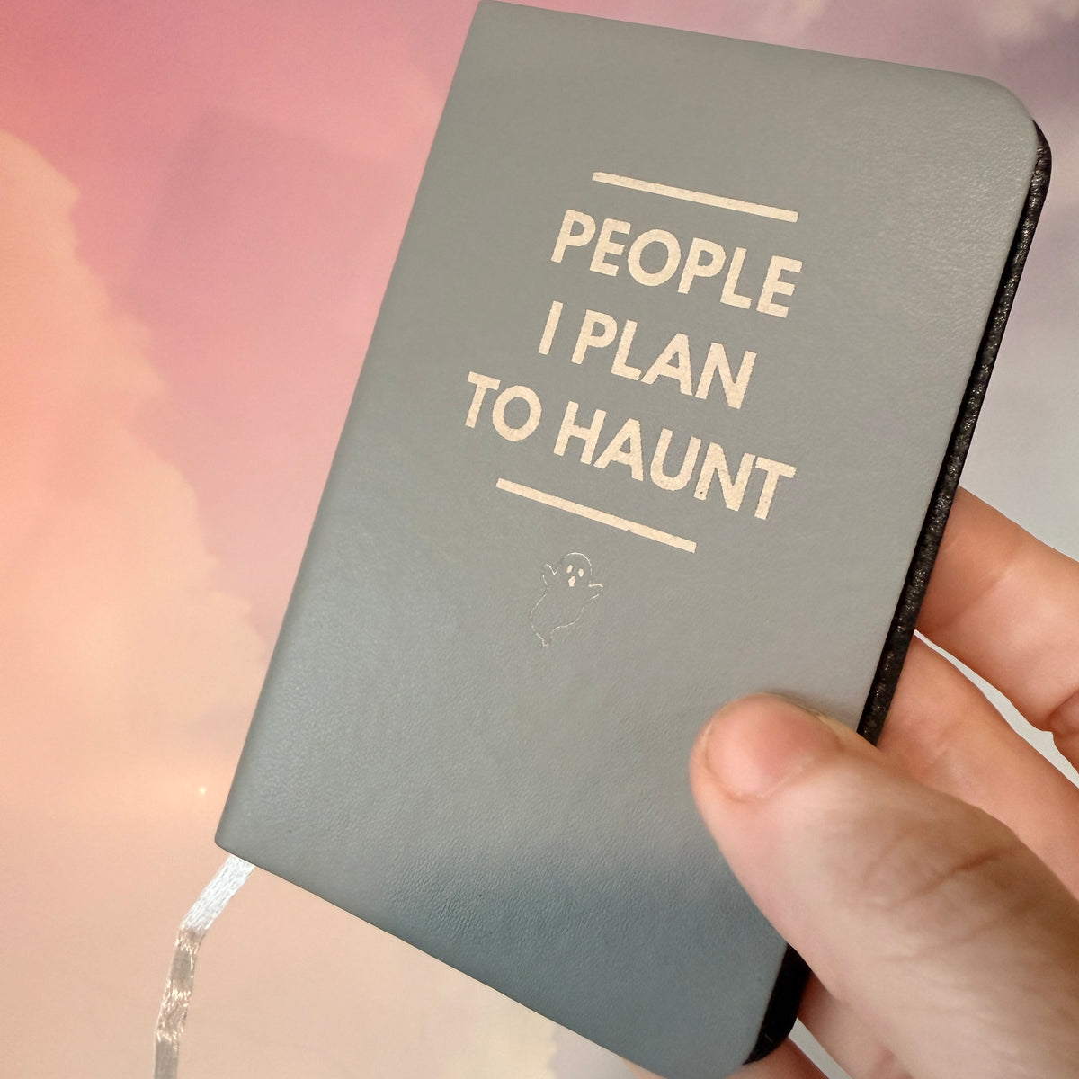 Mini blue notebook with “People I Plan to Haunt” laser engraved in black lettering and a tiny ghost illustration. Approximately 4 x 2.5 inches, with 50 lined pages. Available in brown, green, blue, gray, and black.

