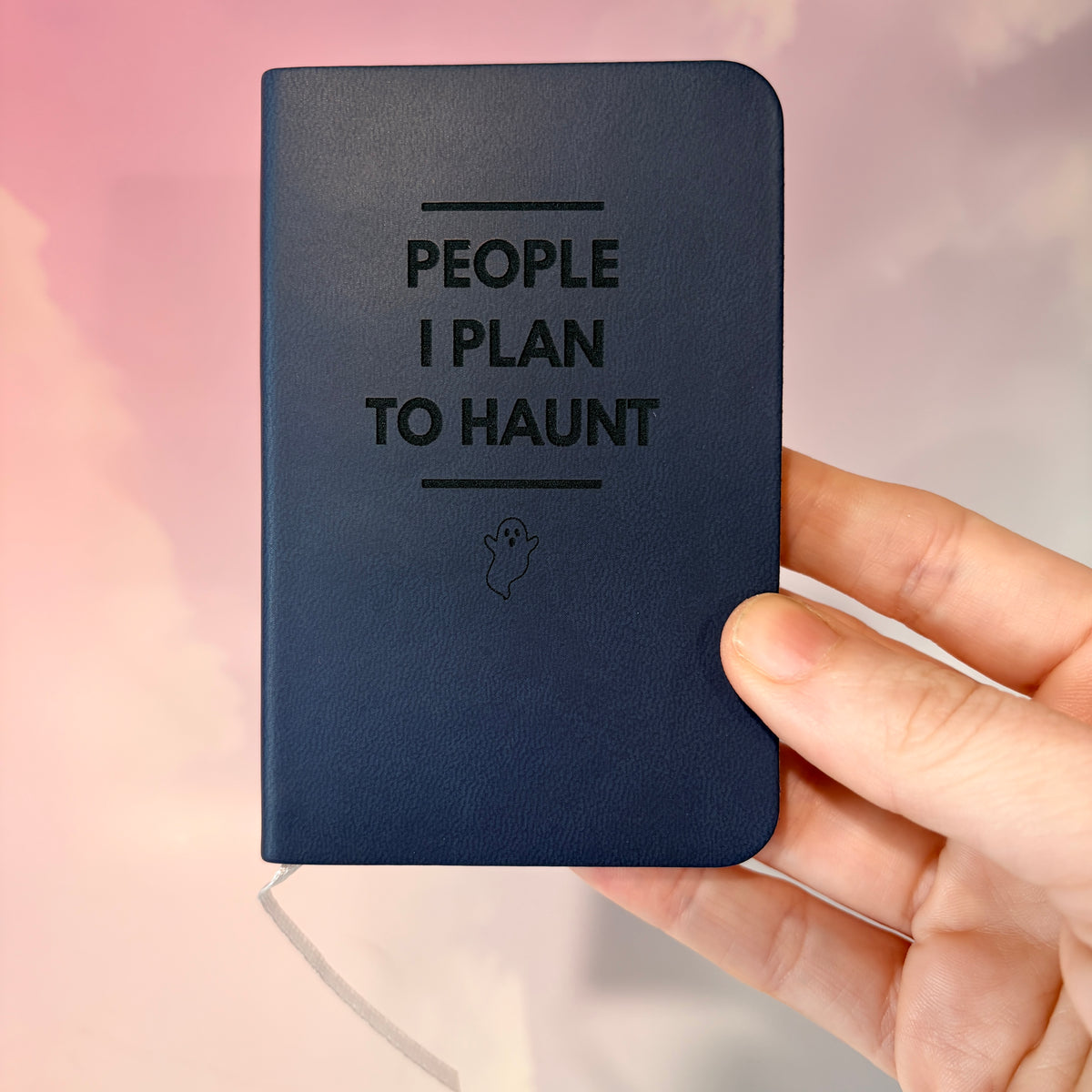 Mini blue notebook with “People I Plan to Haunt” laser engraved in black lettering and a tiny ghost illustration. Approximately 4 x 2.5 inches, with 50 lined pages. Available in brown, green, blue, gray, and black.

