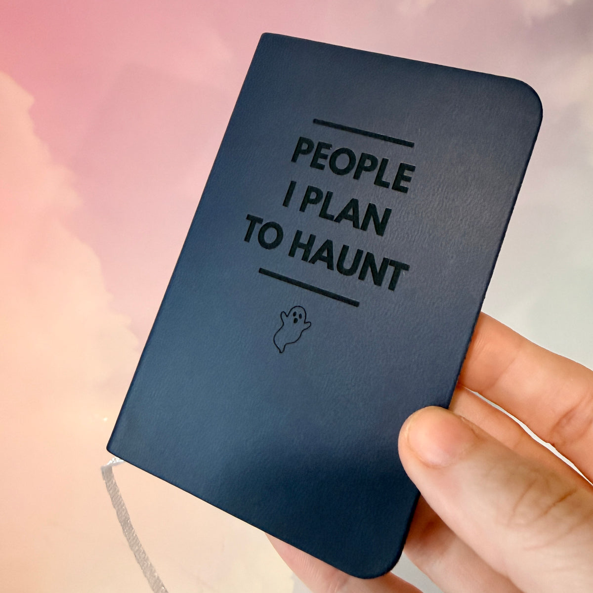 Mini blue notebook with “People I Plan to Haunt” laser engraved in black lettering and a tiny ghost illustration. Approximately 4 x 2.5 inches, with 50 lined pages. Available in brown, green, blue, gray, and black.
