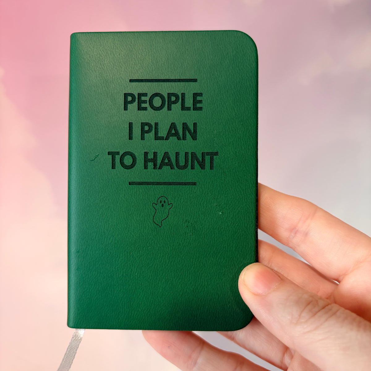 Mini blue notebook with “People I Plan to Haunt” laser engraved in black lettering and a tiny ghost illustration. Approximately 4 x 2.5 inches, with 50 lined pages. Available in brown, green, blue, gray, and black.
