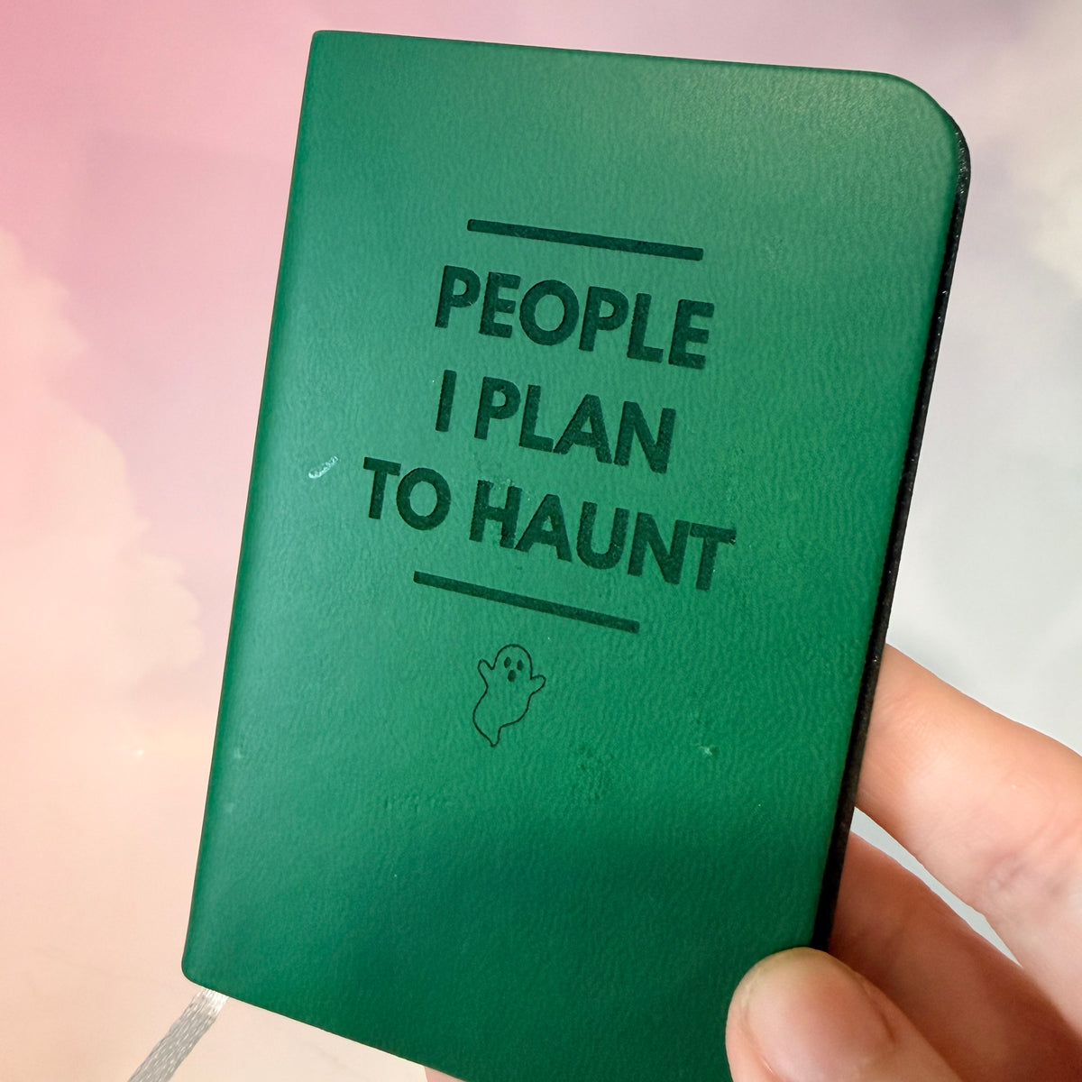 Mini blue notebook with “People I Plan to Haunt” laser engraved in black lettering and a tiny ghost illustration. Approximately 4 x 2.5 inches, with 50 lined pages. Available in brown, green, blue, gray, and black.
