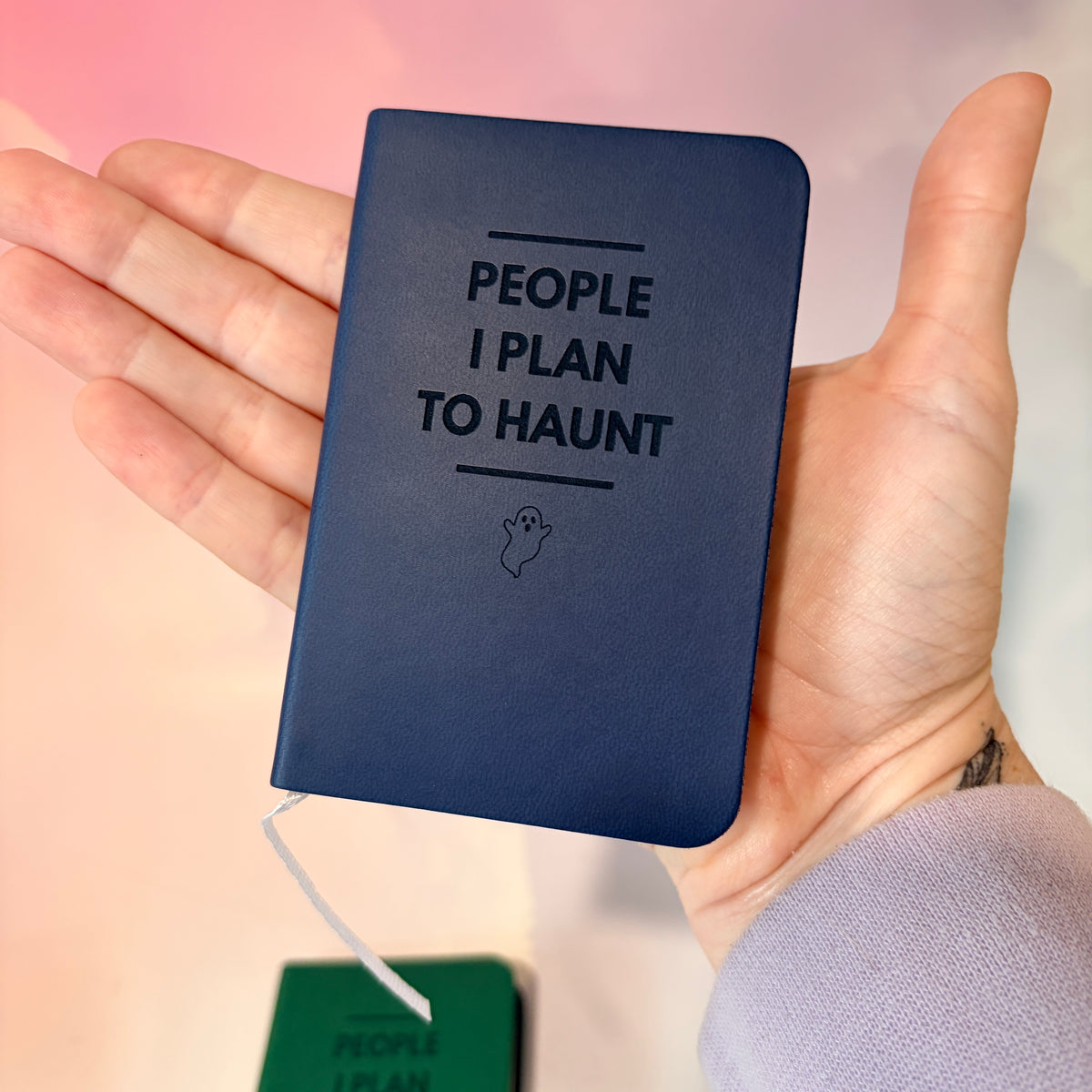 Mini blue notebook with “People I Plan to Haunt” laser engraved in black lettering and a tiny ghost illustration. Approximately 4 x 2.5 inches, with 50 lined pages. Available in brown, green, blue, gray, and black.
