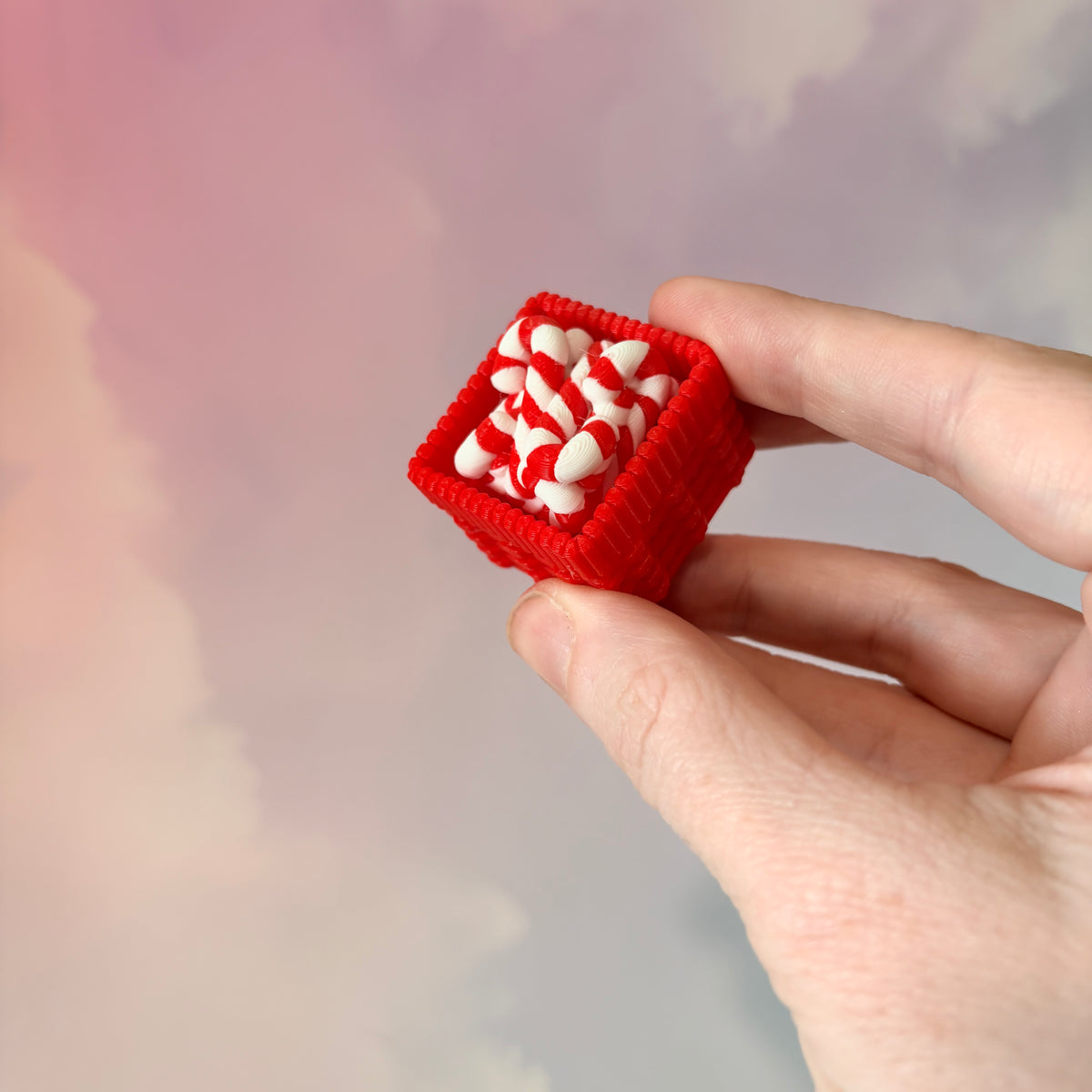 3D printed Christmas fidget clicker featuring a red basket filled with red-and-white candy canes. Available with a clicky or silent mechanism. A festive holiday sensory toy and stocking stuffer for Christmas lovers.