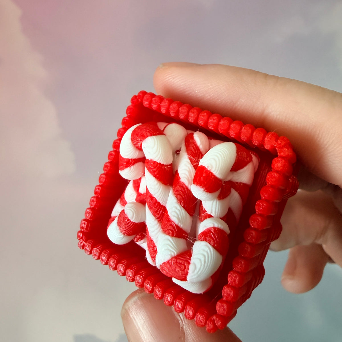 3D printed Christmas fidget clicker featuring a red basket filled with red-and-white candy canes. Available with a clicky or silent mechanism. A festive holiday sensory toy and stocking stuffer for Christmas lovers.