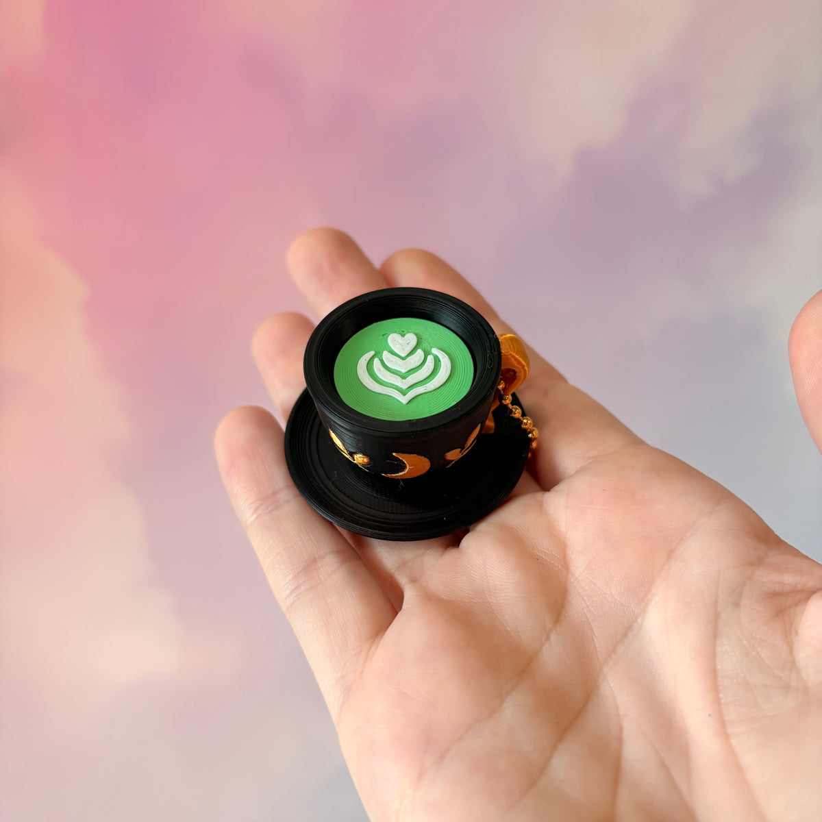 3D printed mystical drink cup fidget clicker keychain with a black floral moon design in gold or silver. Choose matcha or coffee with cute latte art, plus a clicky or silent mechanism.