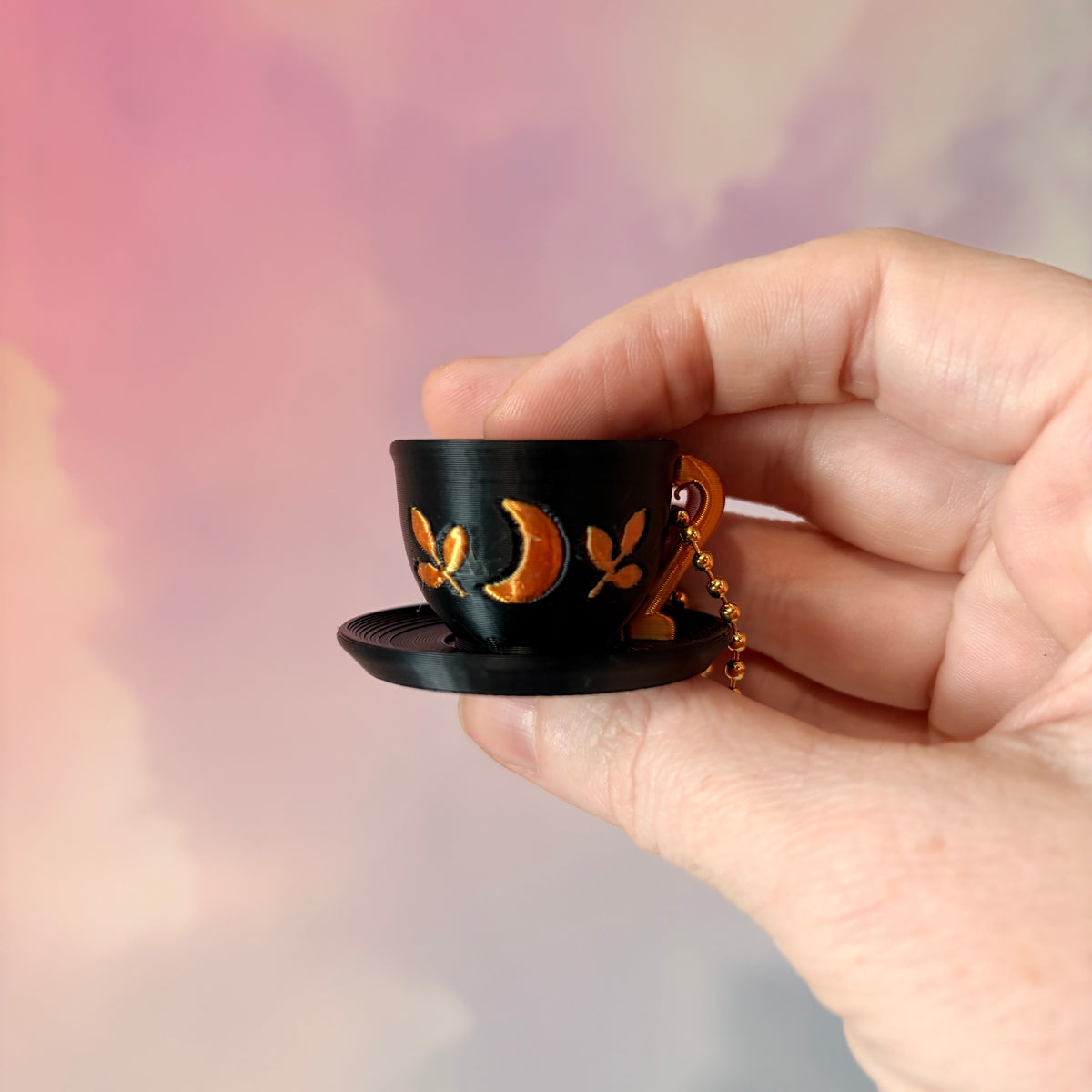 3D printed mystical drink cup fidget clicker keychain with a black floral moon design in gold or silver. Choose matcha or coffee with cute latte art, plus a clicky or silent mechanism.