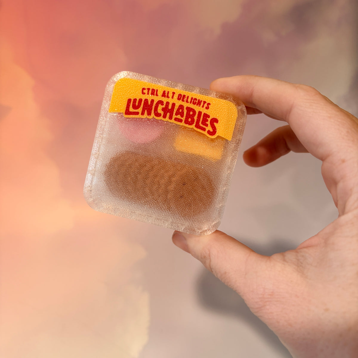 3D printed mini snack box fidget clicker with ham, cheese, and crackers under a semi-transparent lid. Ham and cheese have soft silent presses, while the crackers make satisfying audible clicks.