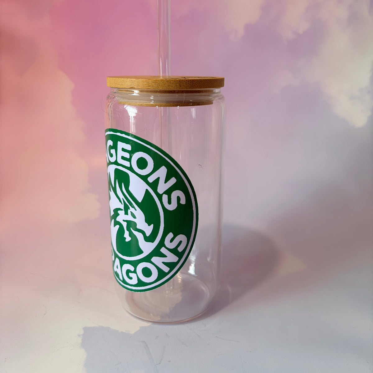 16 oz Dungeons and Dragons glass coffee can with vinyl fantasy design, bamboo lid engraved with two D20 dice, and straw. Custom colors available. Handwash only; not dishwasher or microwave safe.