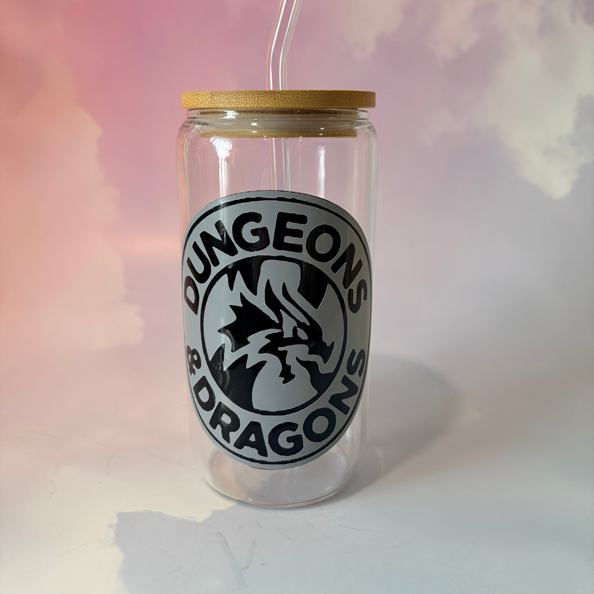 16 oz Dungeons and Dragons glass coffee can with vinyl fantasy design, bamboo lid engraved with two D20 dice, and straw. Custom colors available. Handwash only; not dishwasher or microwave safe.