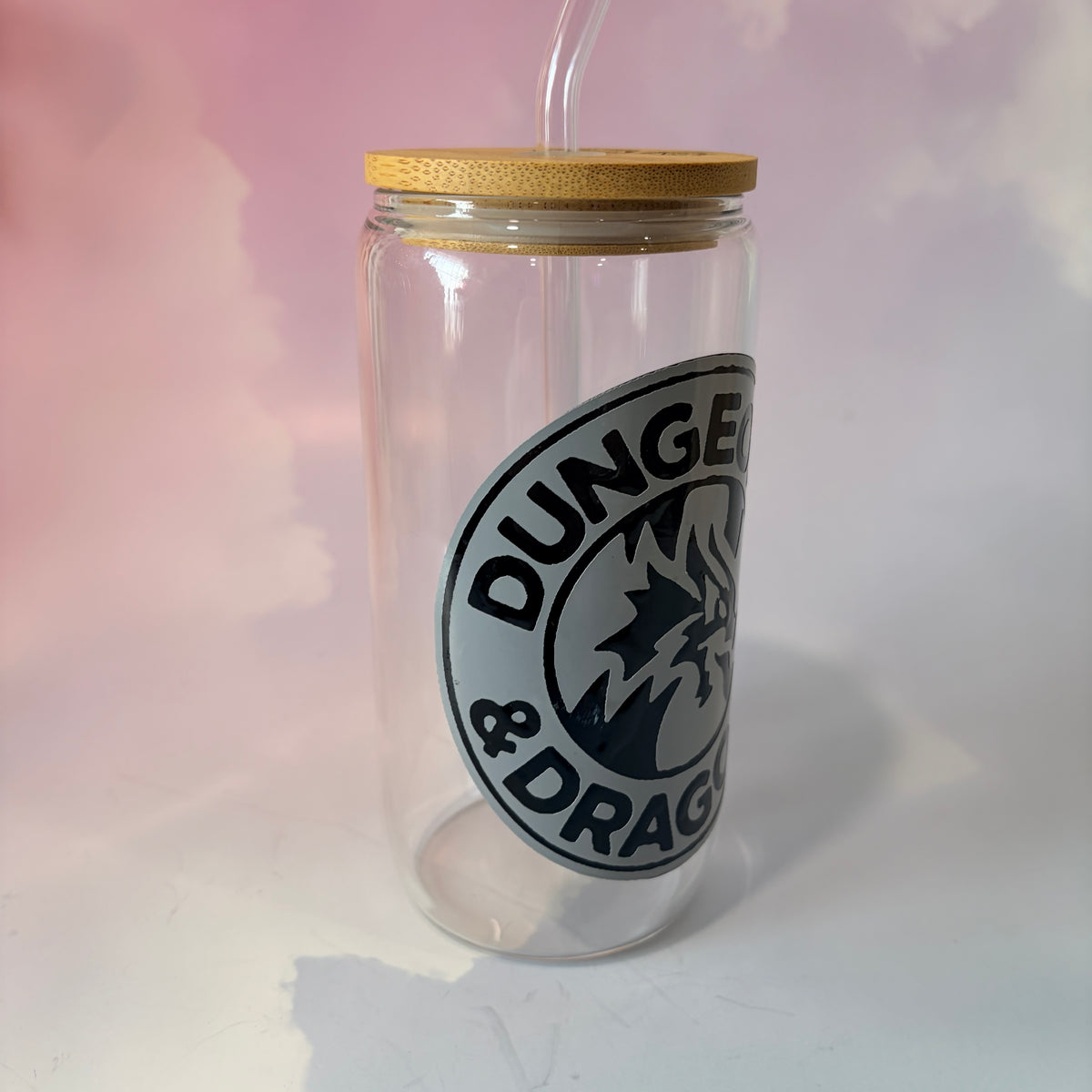 16 oz Dungeons and Dragons glass coffee can with vinyl fantasy design, bamboo lid engraved with two D20 dice, and straw. Custom colors available. Handwash only; not dishwasher or microwave safe.