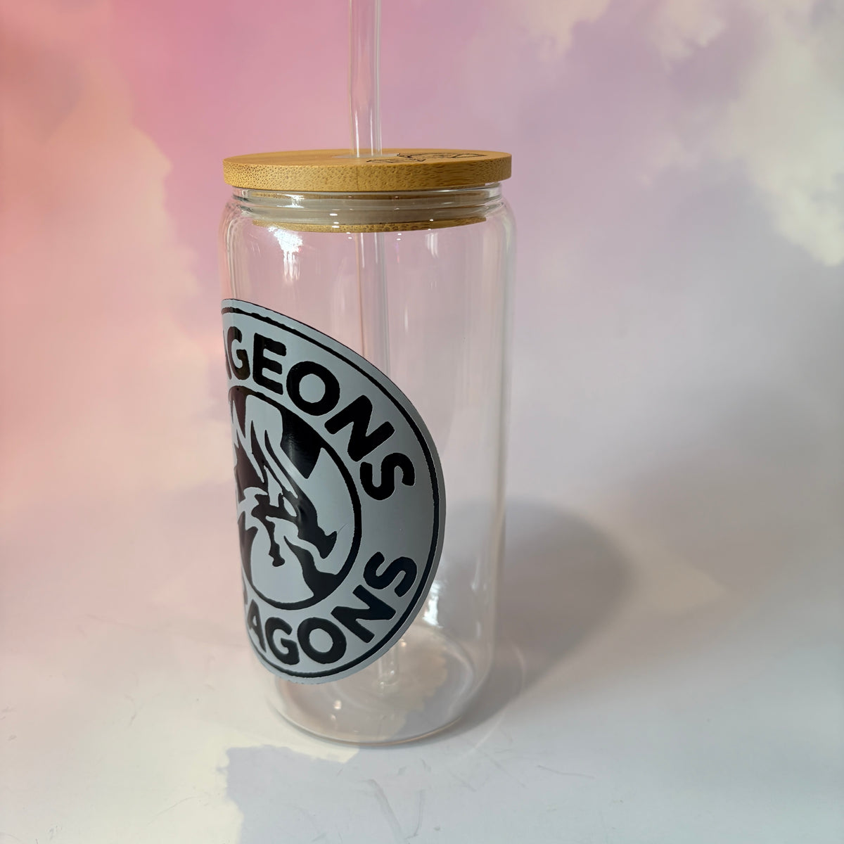 16 oz Dungeons and Dragons glass coffee can with vinyl fantasy design, bamboo lid engraved with two D20 dice, and straw. Custom colors available. Handwash only; not dishwasher or microwave safe.