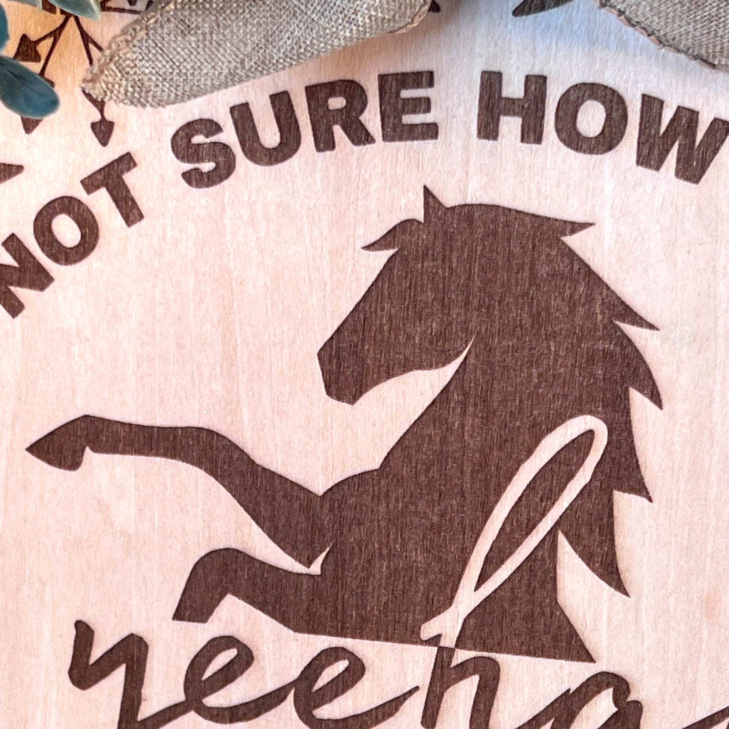 Laser-engraved wood sign featuring 'Not Sure How Many Yeehaws I Got Left,' decorated with a horse silhouette, floral accents, and a rustic bow.