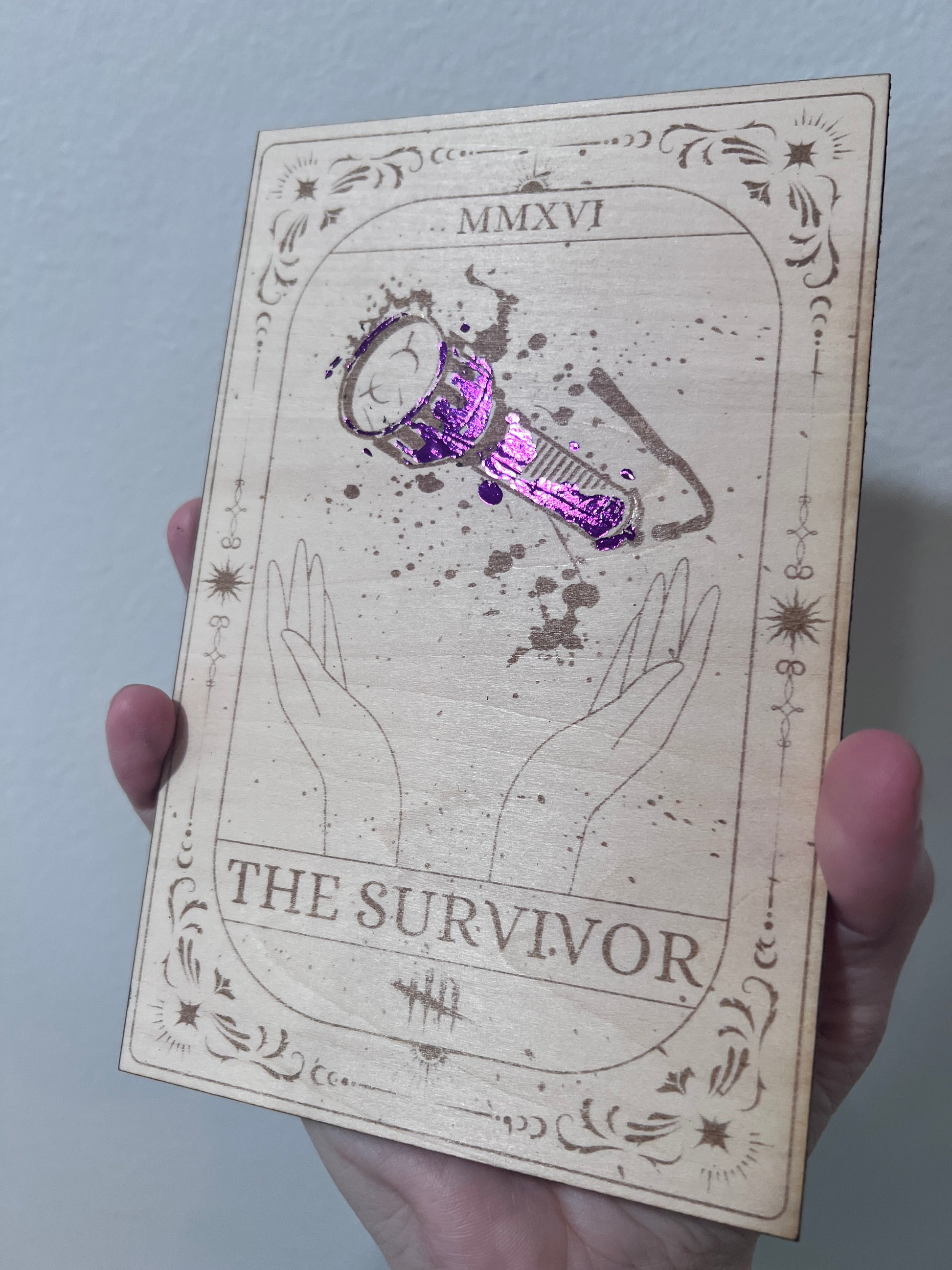 Laser-engraved wooden tarot card inspired by Dead by Daylight, featuring "The Survivor" flashlight design, with purple foiled accents. Horror game decor, perfect for DBD fans and collectors.