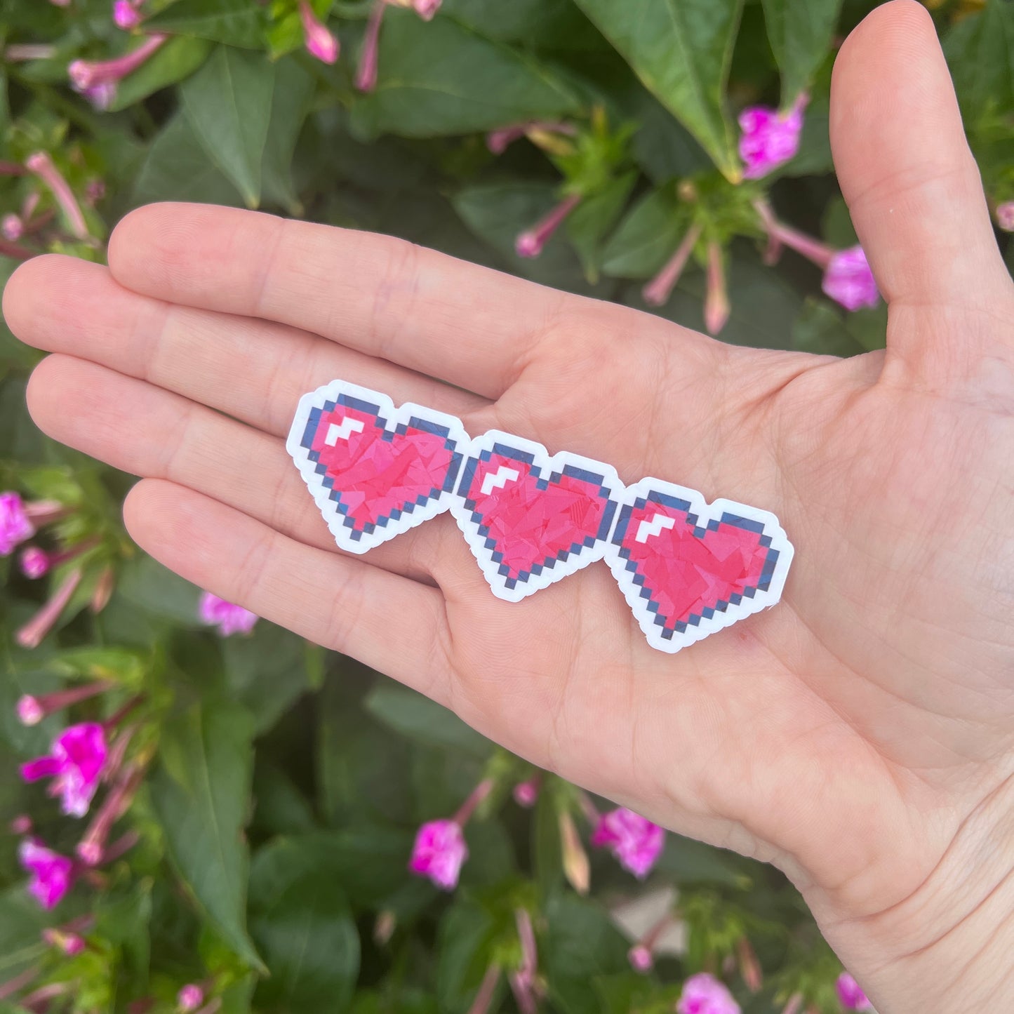Holographic gamer heart sticker featuring 3 red pixel hearts in a heart container design. Perfect for laptops, water bottles, and game-themed journals.