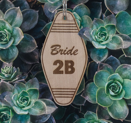 Wooden tag with 'Bride 2B' text on a background of succulents