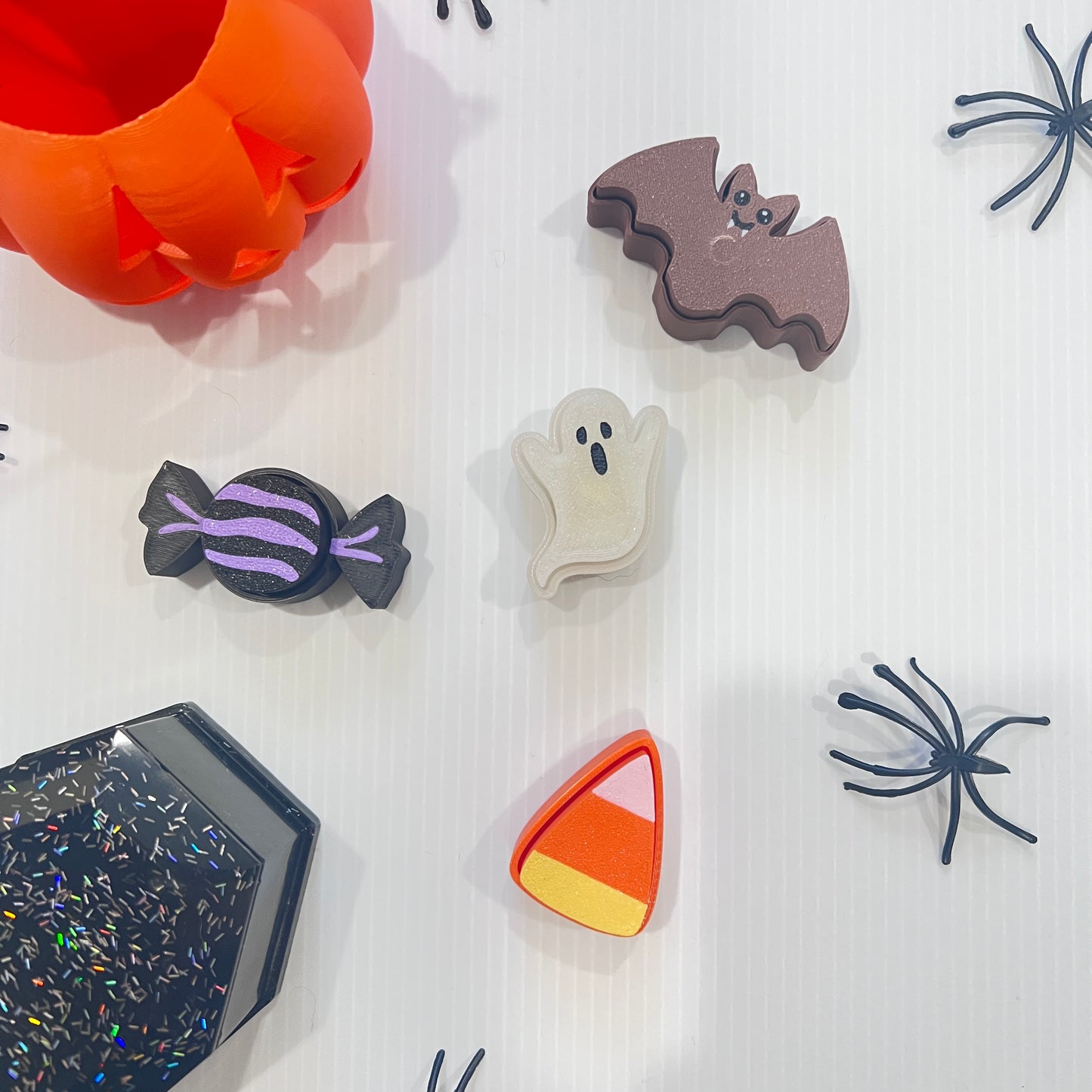 Cute Halloween clicker set with glow-in-the-dark ghost, candy corn, chocolate bat, and wrapped candy fidget toys in a festive pumpkin pail container.