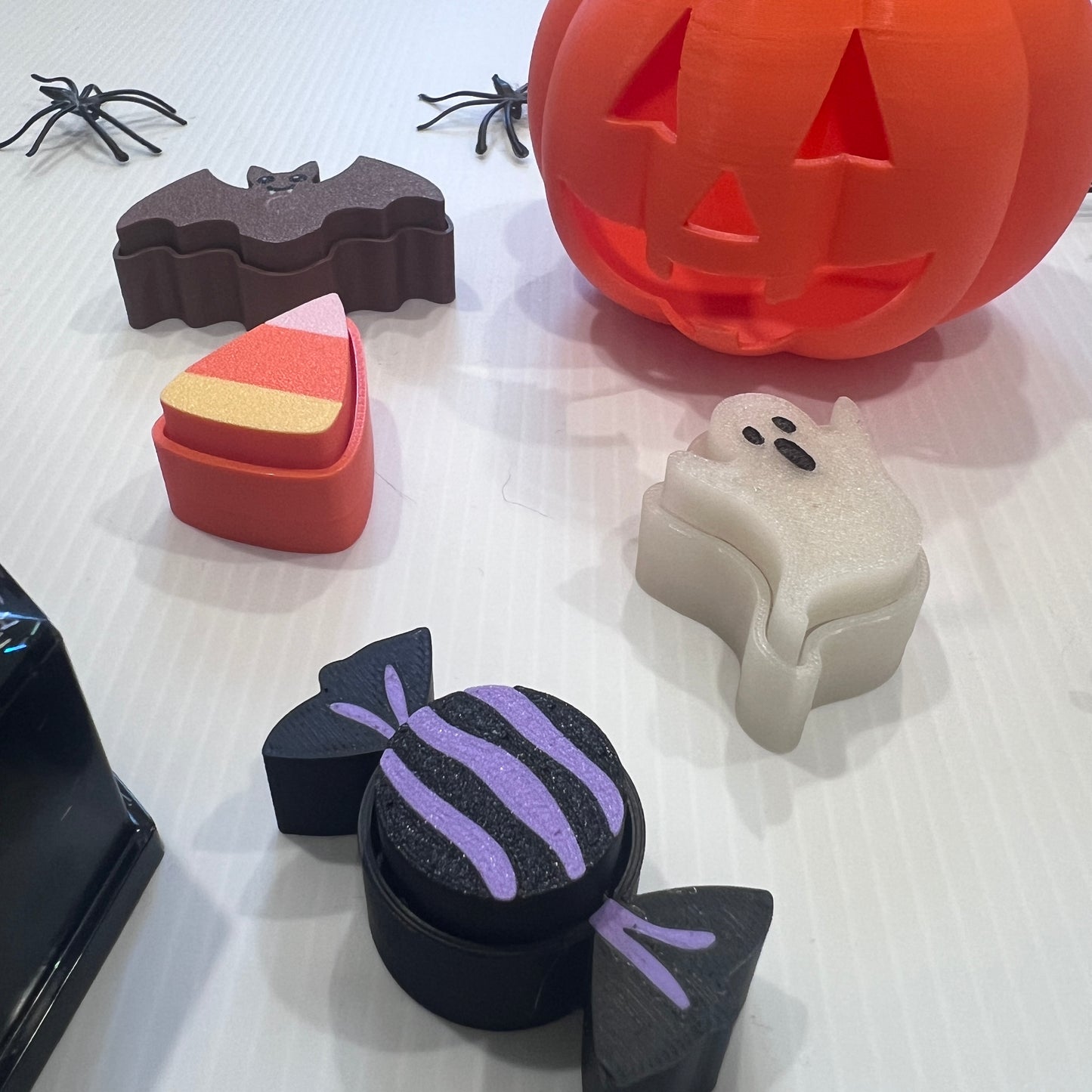 Cute Halloween clicker set with glow-in-the-dark ghost, candy corn, chocolate bat, and wrapped candy fidget toys in a festive pumpkin pail container.