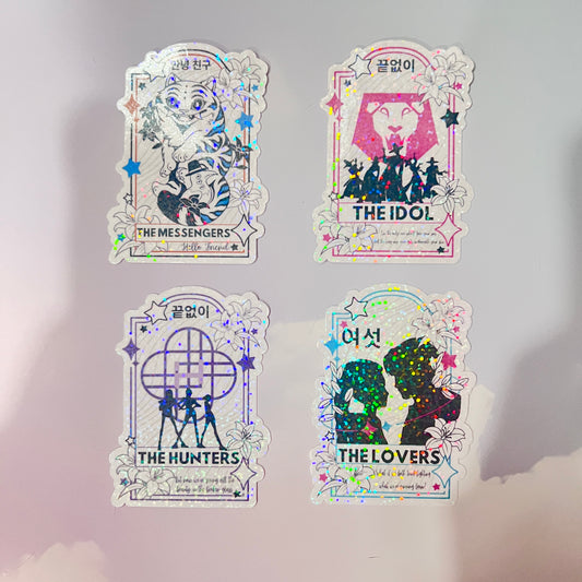Holographic vinyl tarot sticker set featuring KPOP demon hunter characters: Lovers, Idol, Hunters, and Messengers. Vibrant, 3-inch water-resistant decals. Featuring Huntrix, The Saja Boys, Derpy Tiger, and Rumi and Jinu.