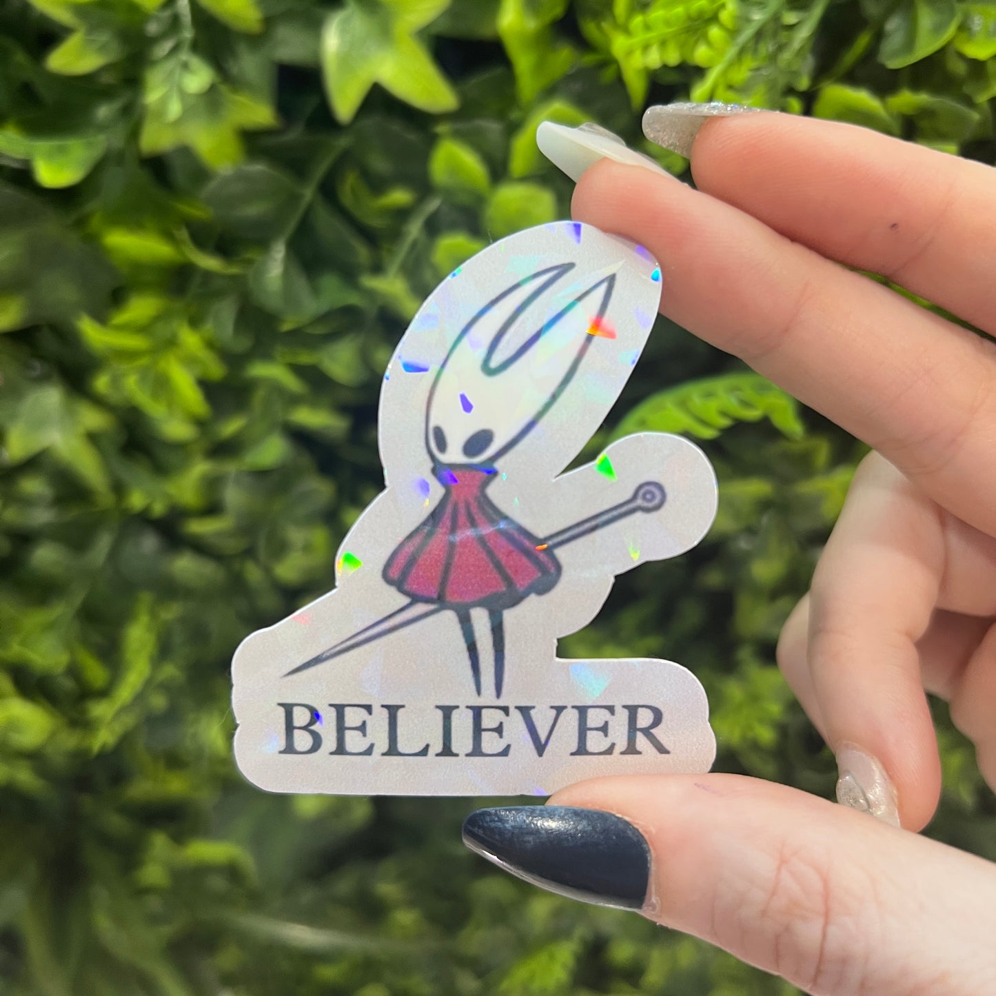 Holographic Hornet “BELIEVER” vinyl sticker inspired by Hollow Knight Silksong. Durable, shiny gamer decal perfect for laptops, water bottles, or journals.