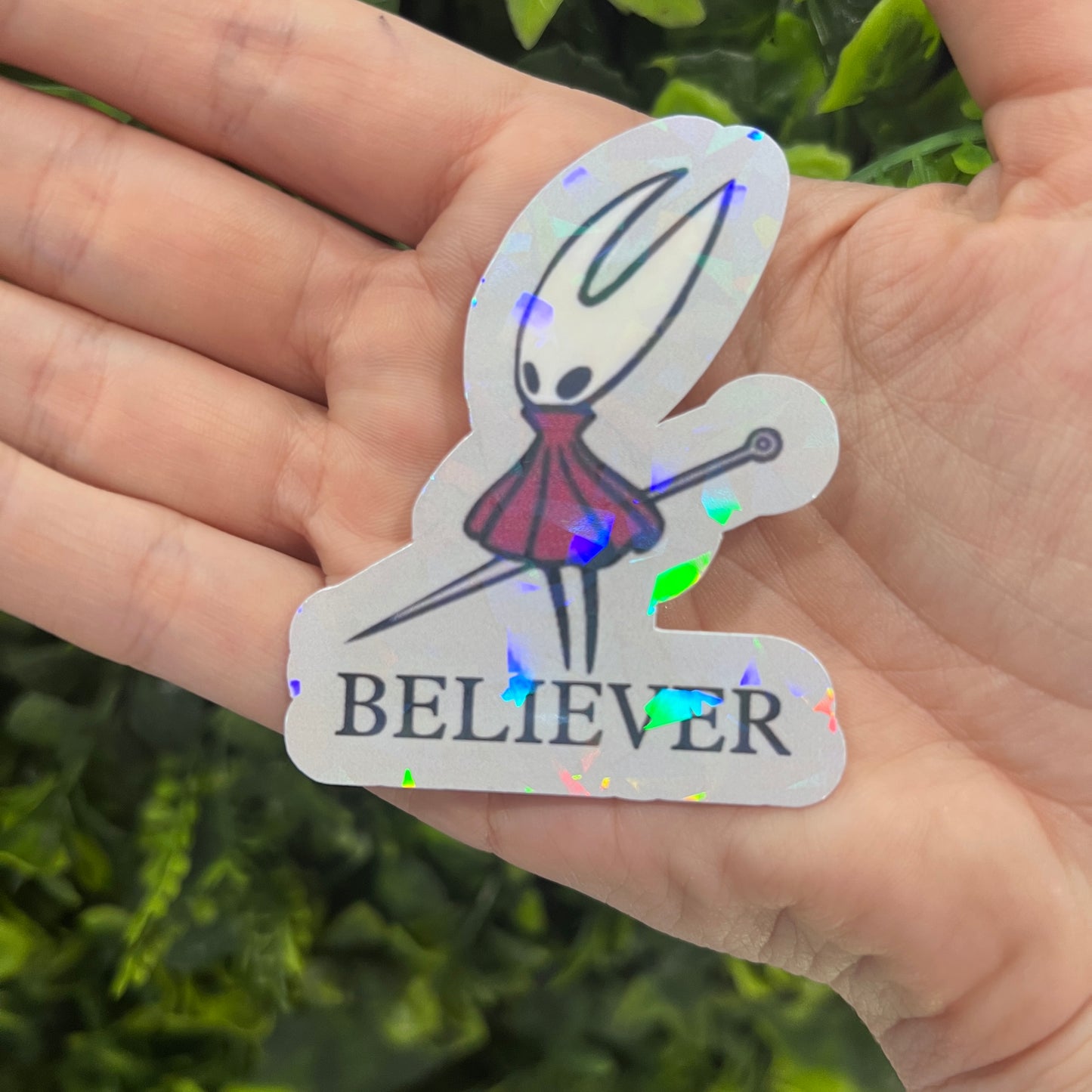 Holographic Hornet “BELIEVER” vinyl sticker inspired by Hollow Knight Silksong. Durable, shiny gamer decal perfect for laptops, water bottles, or journals.