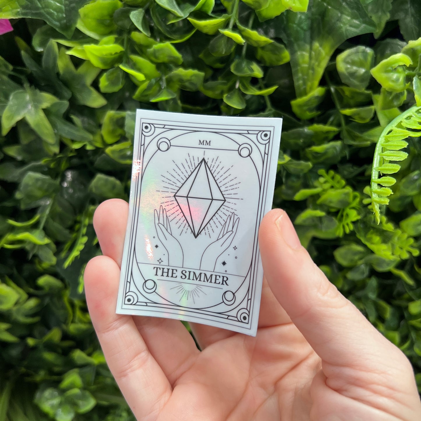 Silver Holographic Sims tarot card sticker featuring "The Simmer" with a radiant plumbob design. A must-have for Sims fans, gamers, and lovers of geeky decor.