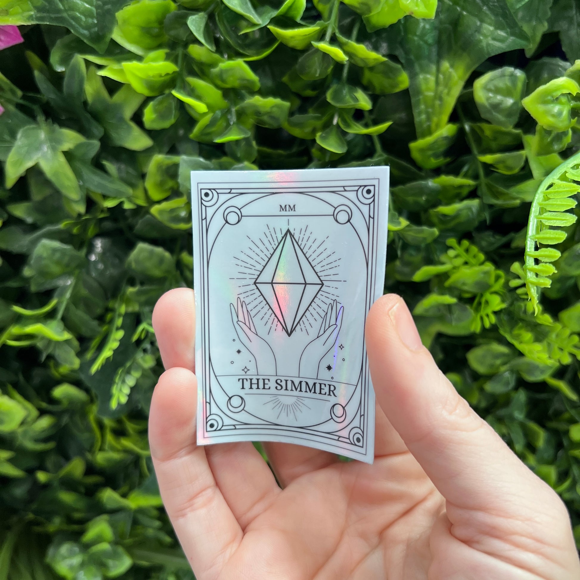 Silver Holographic Sims tarot card sticker featuring "The Simmer" with a radiant plumbob design. A must-have for Sims fans, gamers, and lovers of geeky decor.