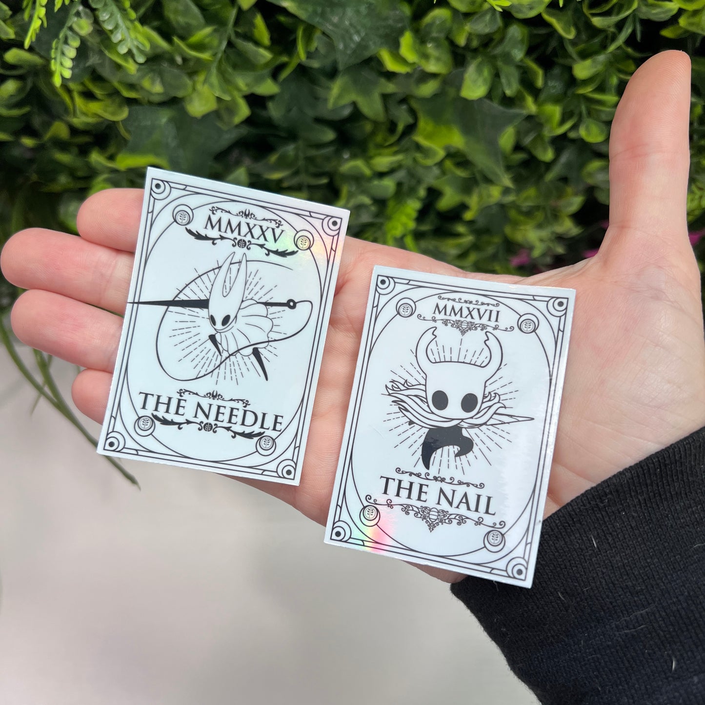 Silver Holographic tarot card stickers featuring Hollow Knight as The Nail and Hornet as the Needle. Unique indie game fan art collectible.