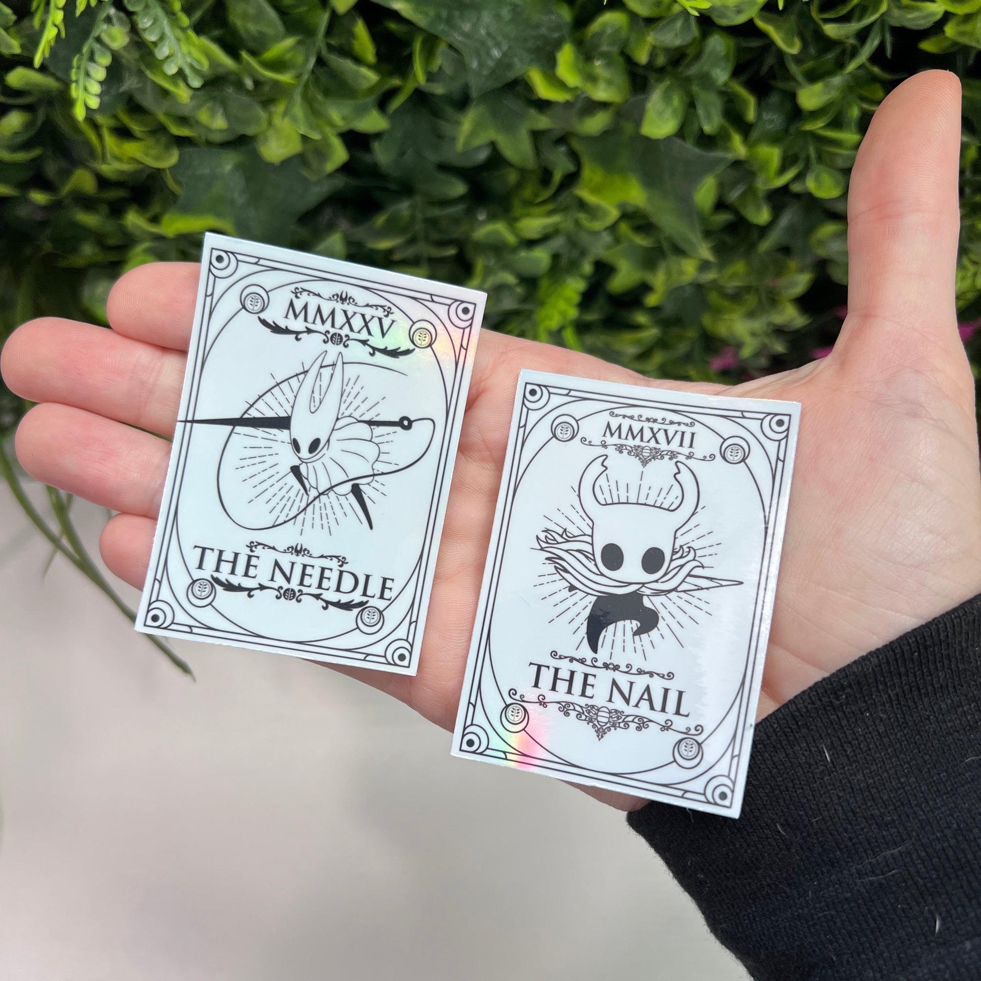 Silver Holographic tarot card stickers featuring Hollow Knight as The Nail and Hornet as the Needle. Unique indie game fan art collectible.