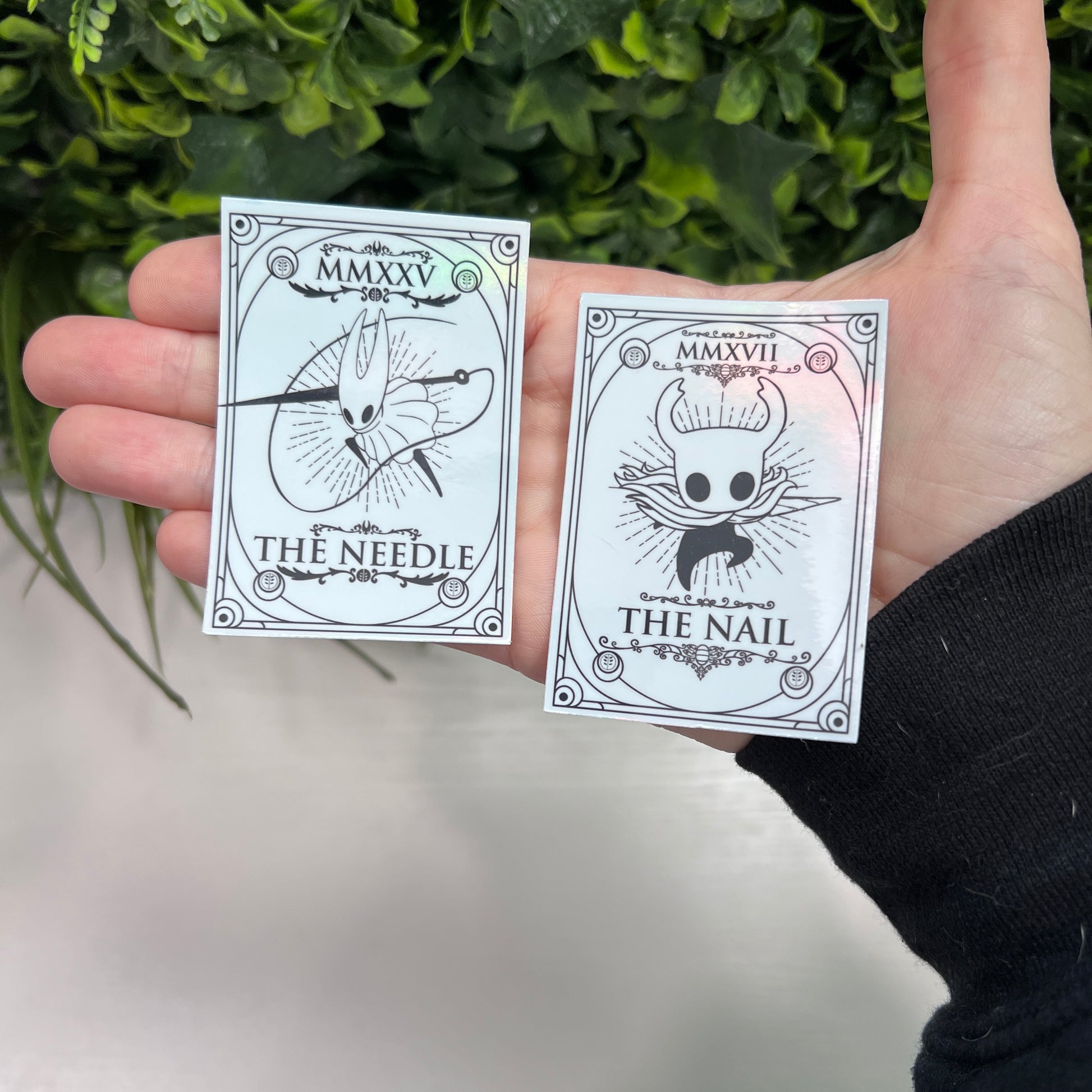 Silver Holographic tarot card stickers featuring Hollow Knight as The Nail and Hornet as the Needle. Unique indie game fan art collectible.