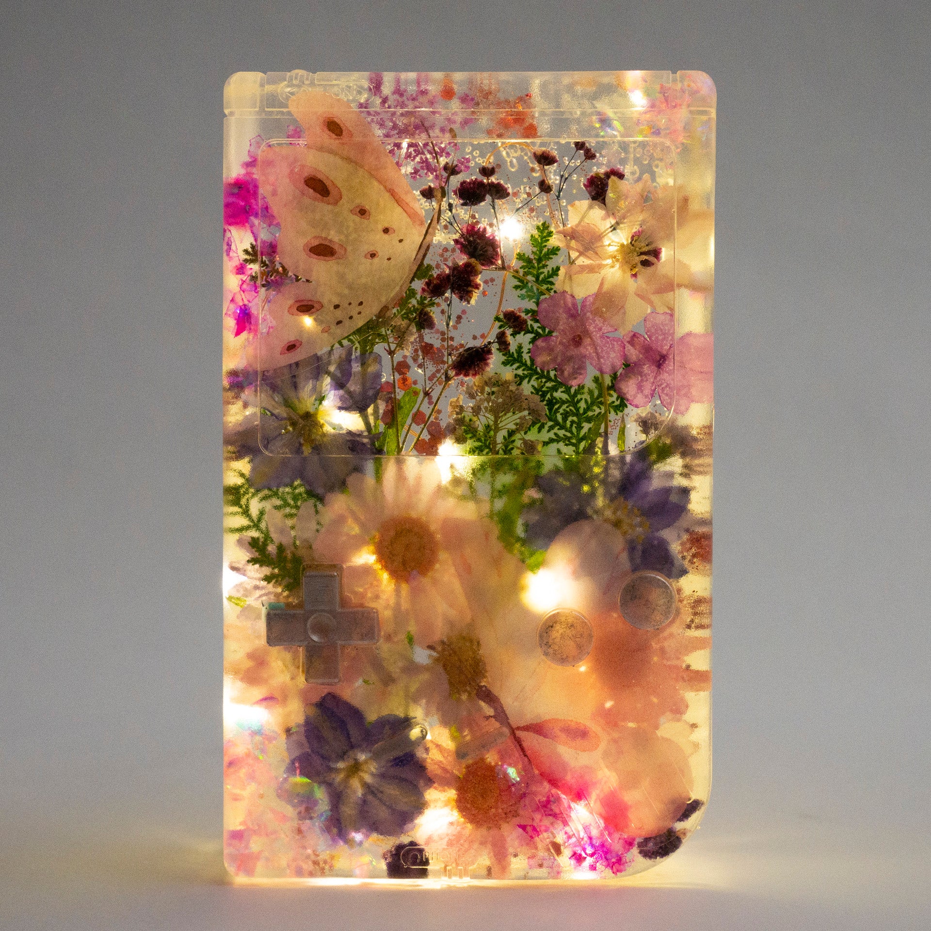 Customizable resin Gameboy with pressed flowers and glitter embedded in clear resin. Perfect for collectors and gaming fans alike.