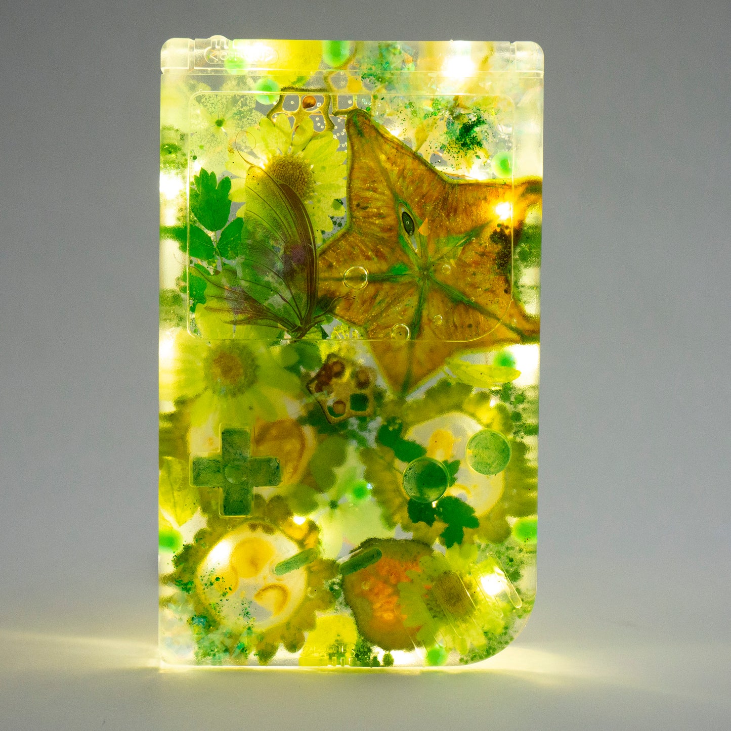 Customizable resin Gameboy with pressed flowers and glitter embedded in clear resin. Perfect for collectors and gaming fans alike.
