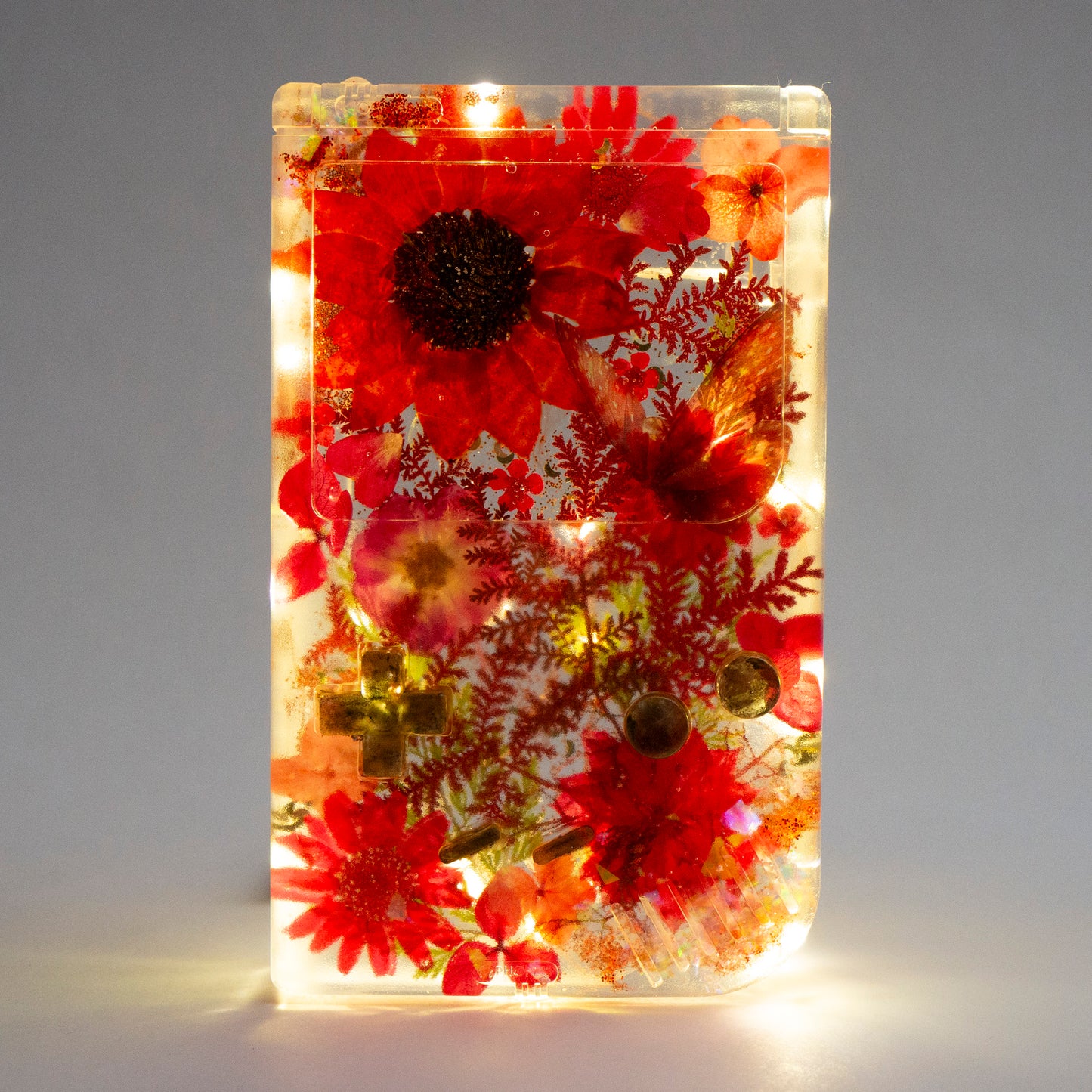 Customizable resin Gameboy with pressed flowers and glitter embedded in clear resin. Perfect for collectors and gaming fans alike.
