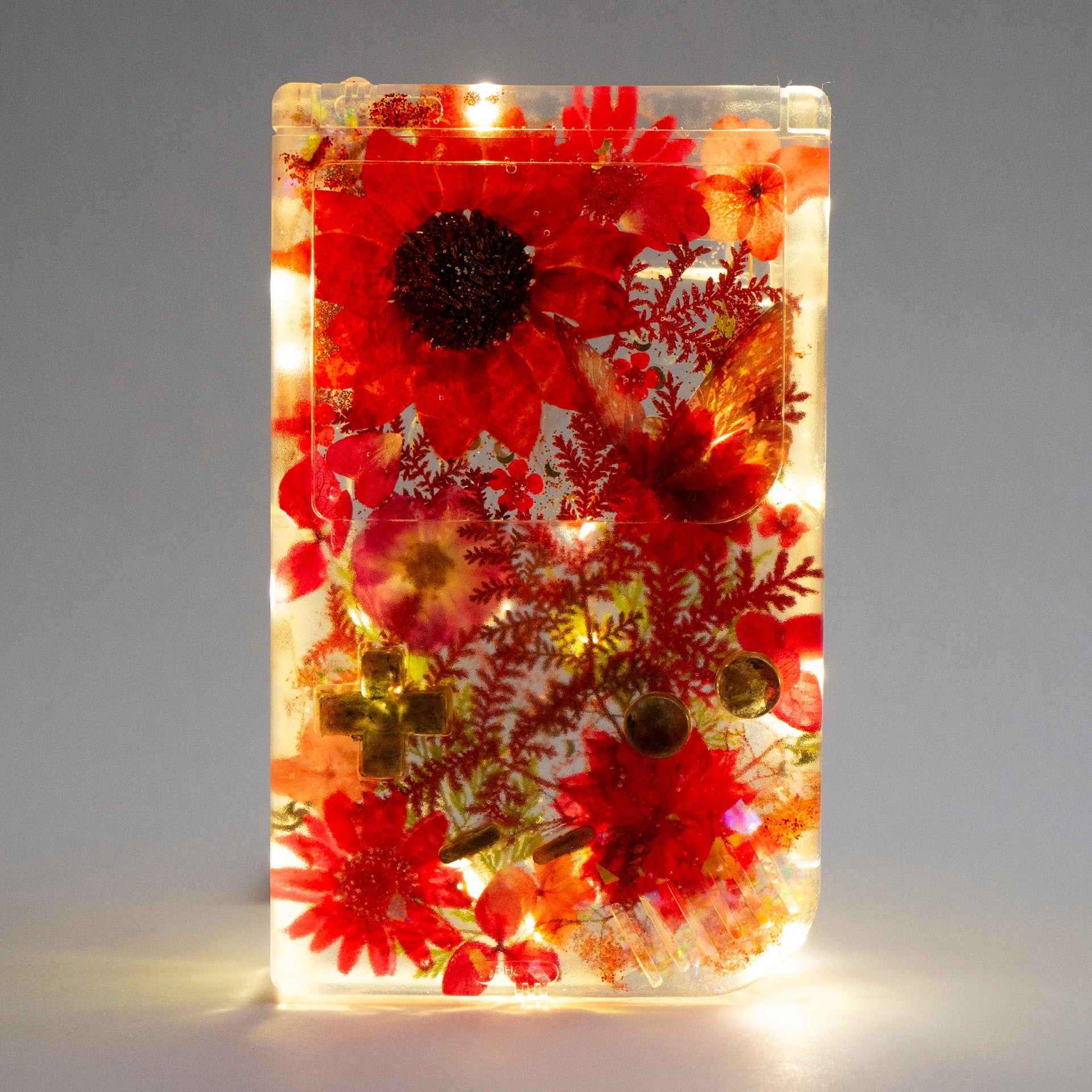 Customizable resin Gameboy with pressed flowers and glitter embedded in clear resin. Perfect for collectors and gaming fans alike.