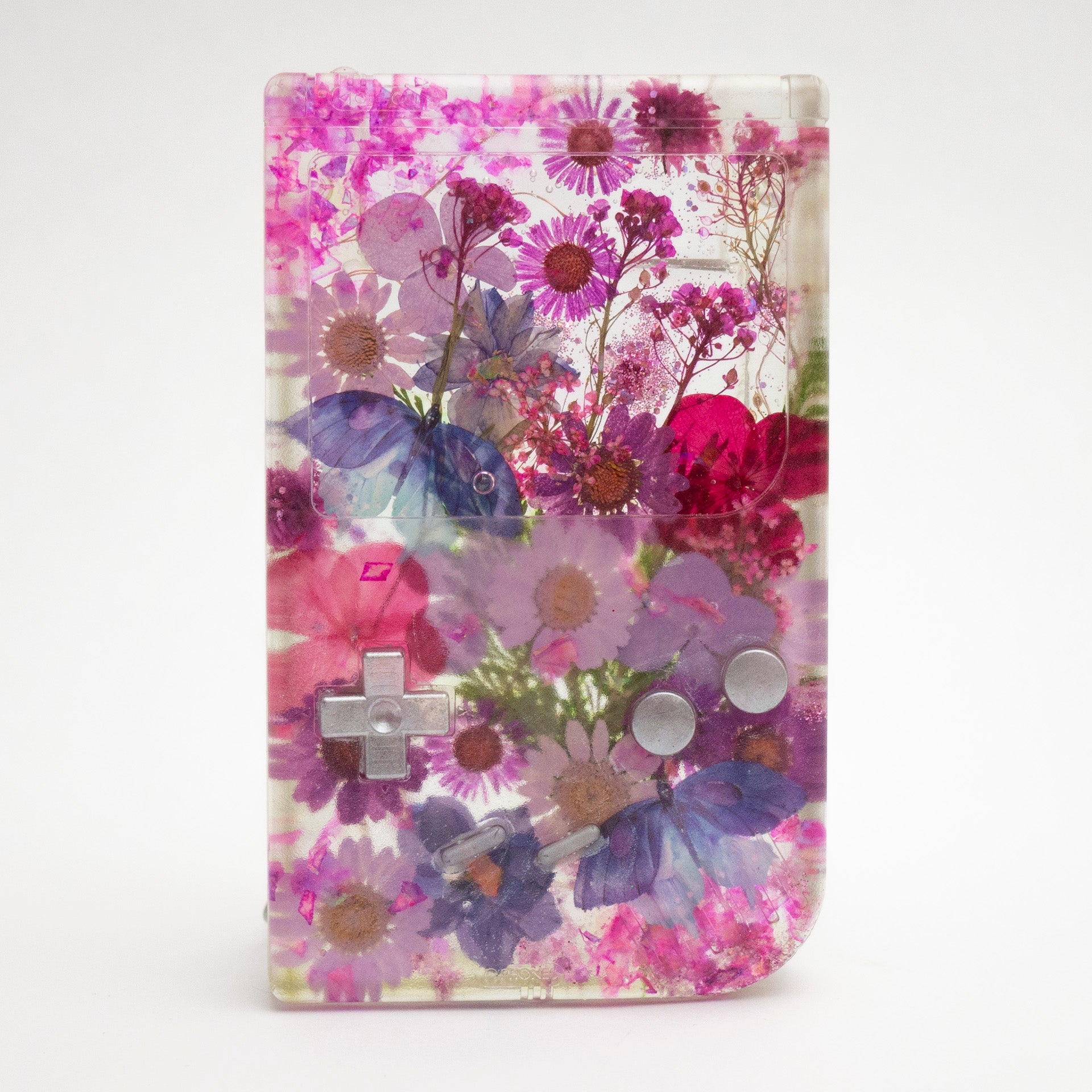 Customizable resin Gameboy with pressed flowers and glitter embedded in clear resin. Perfect for collectors and gaming fans alike.