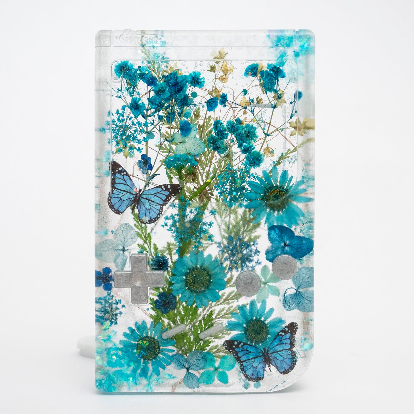 Customizable resin Gameboy with pressed flowers and glitter embedded in clear resin. Perfect for collectors and gaming fans alike.