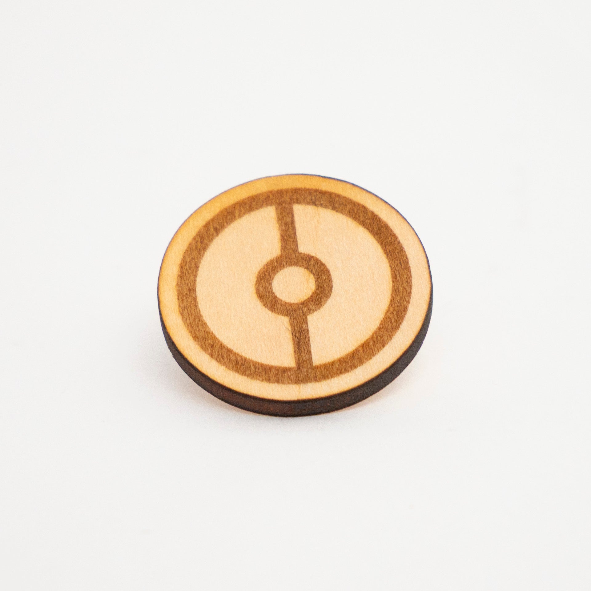 a wooden Poké Ball pin against a white background