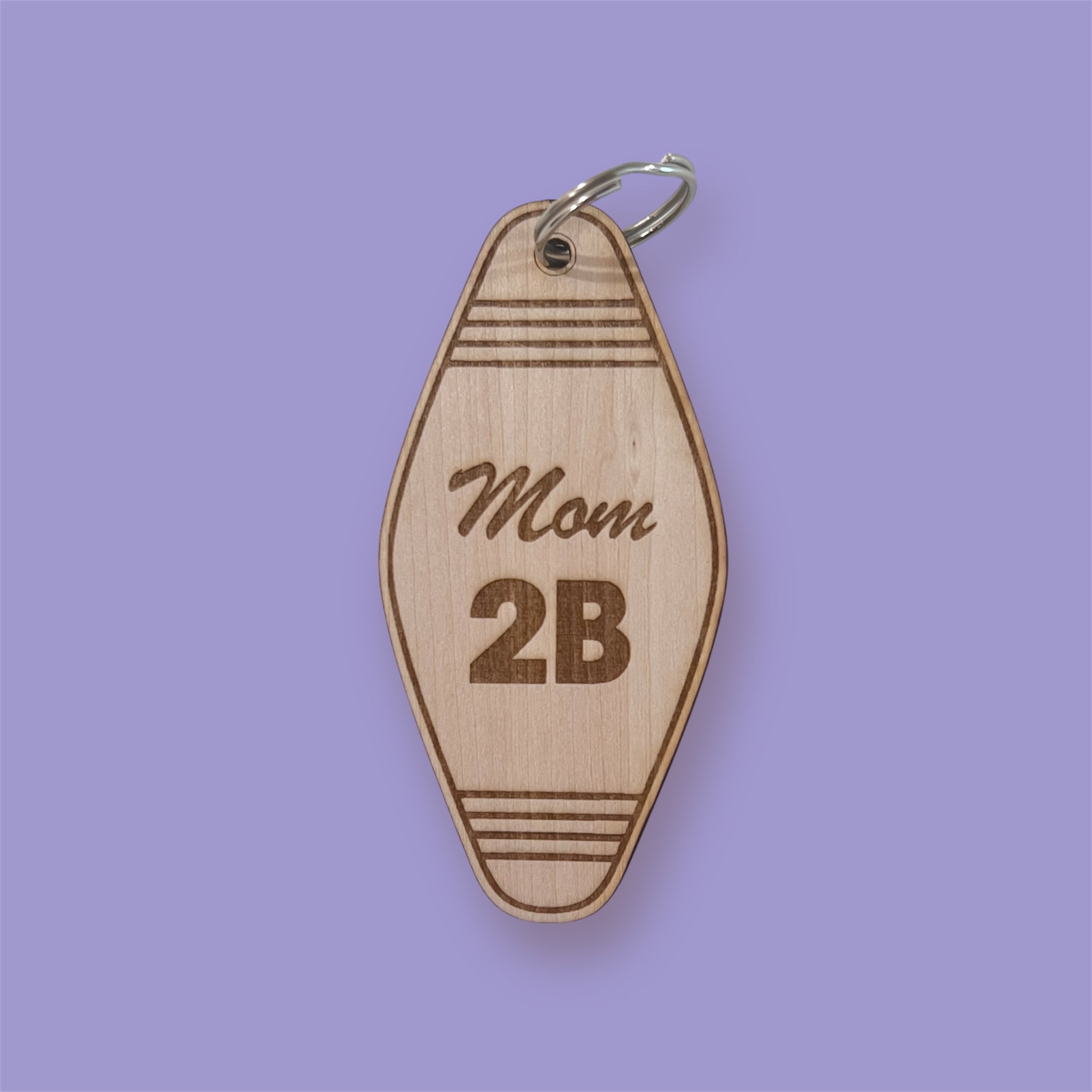 Wooden keychain with 'Mom 2B' engraving on a purple background