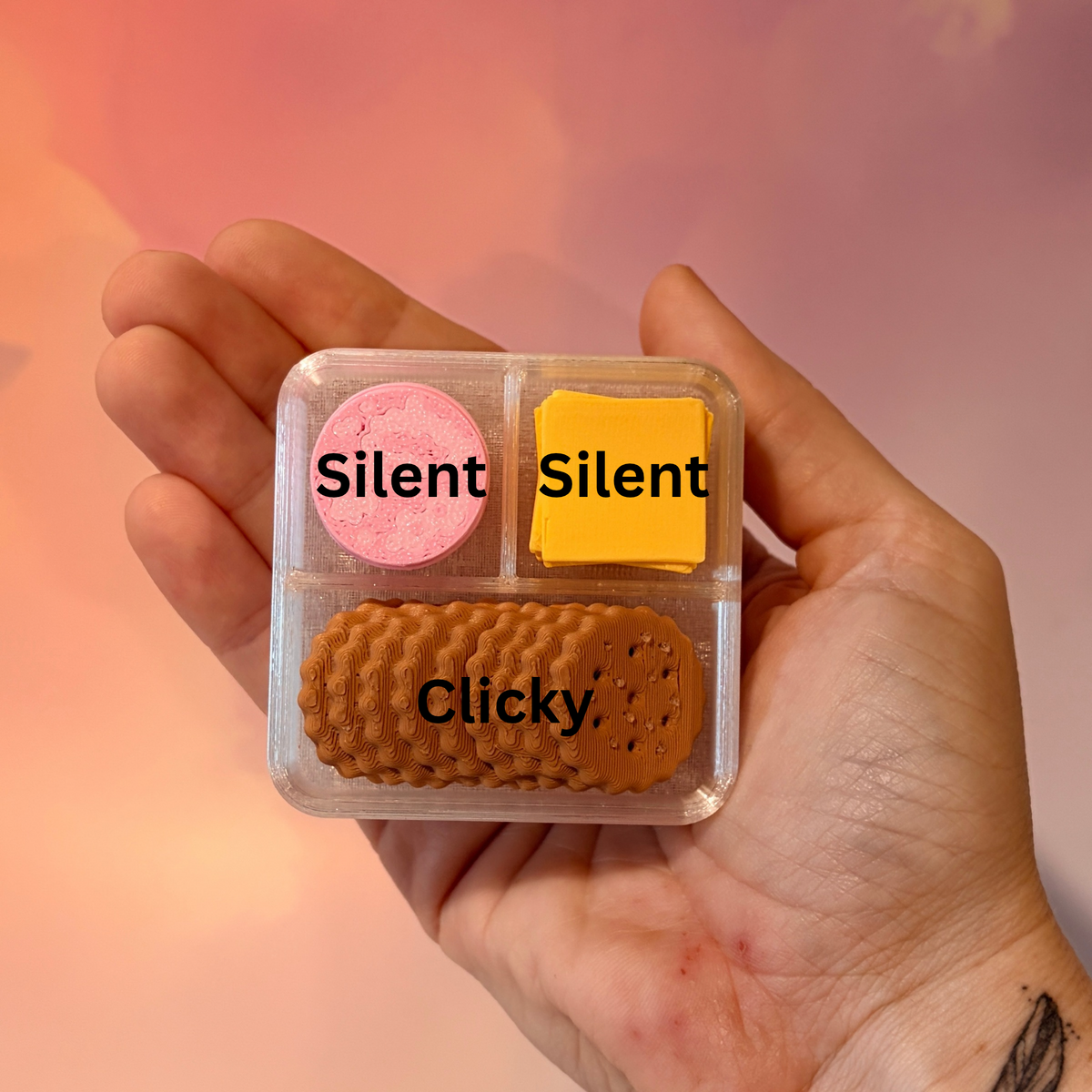 3D printed mini snack box fidget clicker with ham, cheese, and crackers under a semi-transparent lid. Ham and cheese have soft silent presses, while the crackers make satisfying audible clicks.