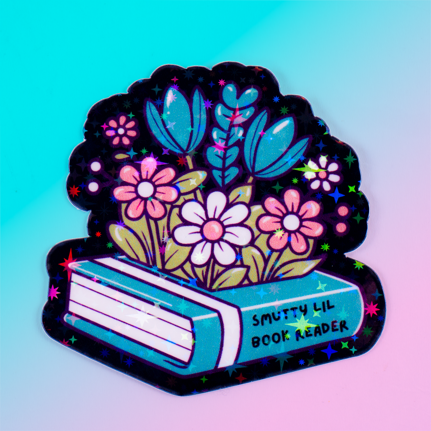 Holographic vinyl sticker featuring flowers growing from a romance book labeled "Smutty Lil Book Reader." Perfect for book lovers, Kindle cases, and bookish decor.