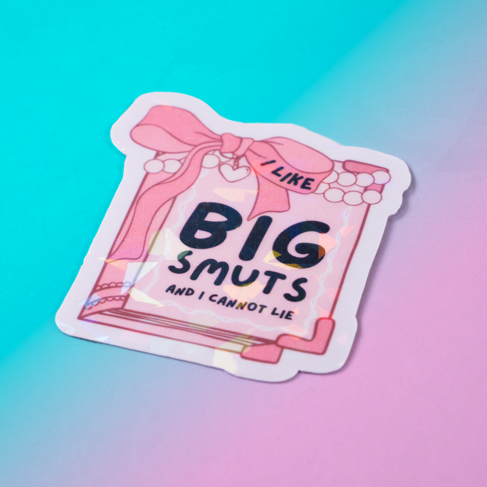 Holographic vinyl sticker featuring a pink book with pearls and the phrase I Like Big Smuts and I Cannot Lie. Perfect for romance book lovers, spicy book readers, and bookish aesthetic fans.