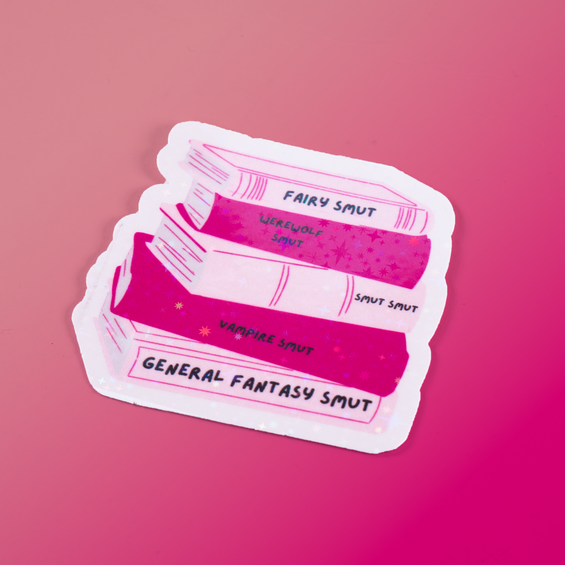 Holographic sticker featuring a pink book stack labeled Fairy Smut, Werewolf Smut, Vampire Smut, and more. A must-have for fantasy romance and spicy book lovers!