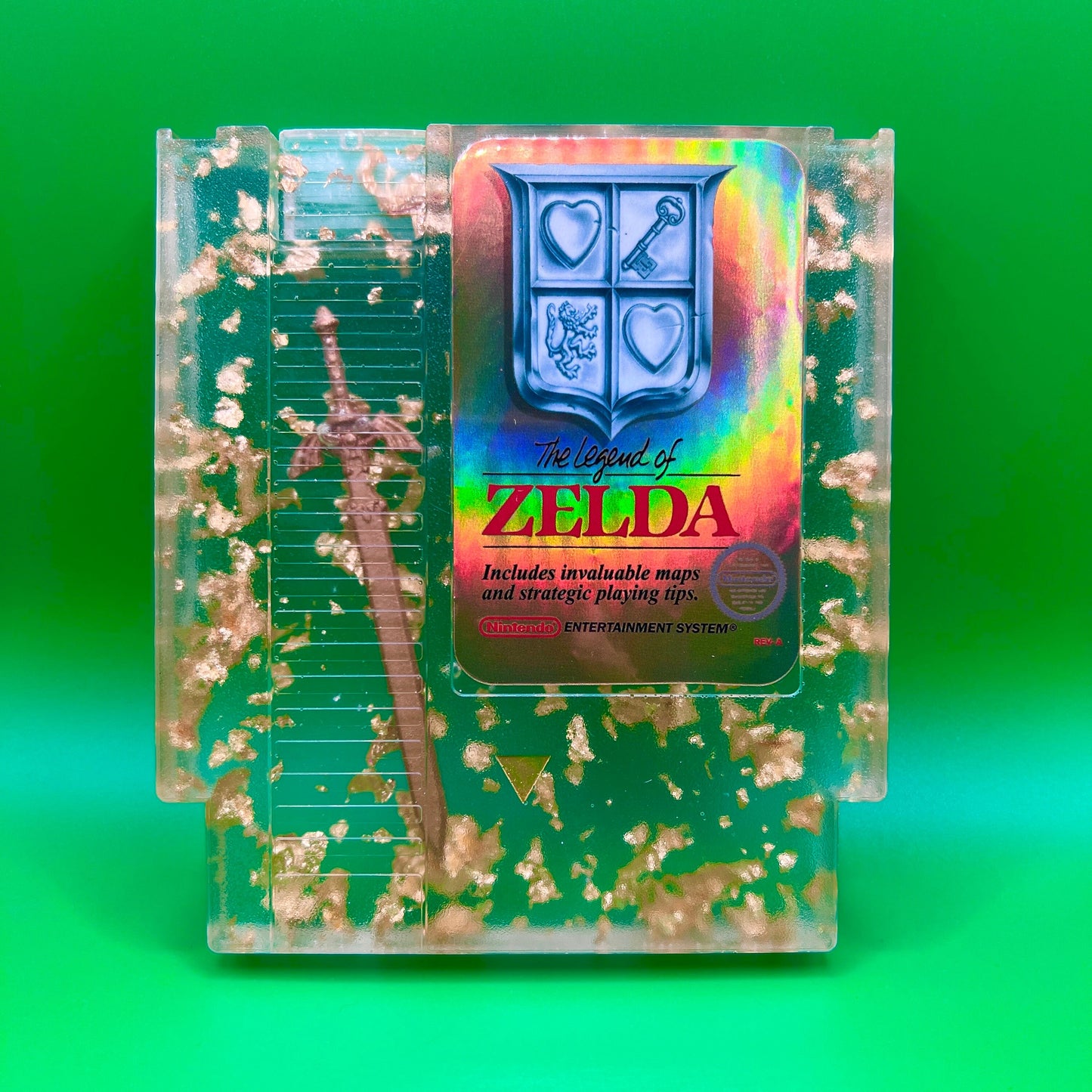 Legend of Zelda resin art featuring a retro NES cartridge with a gold sword design and gold flakes embedded. This handmade display is perfect for gamers and video game collectors, offering a unique décor piece for any gaming setup or retro collection