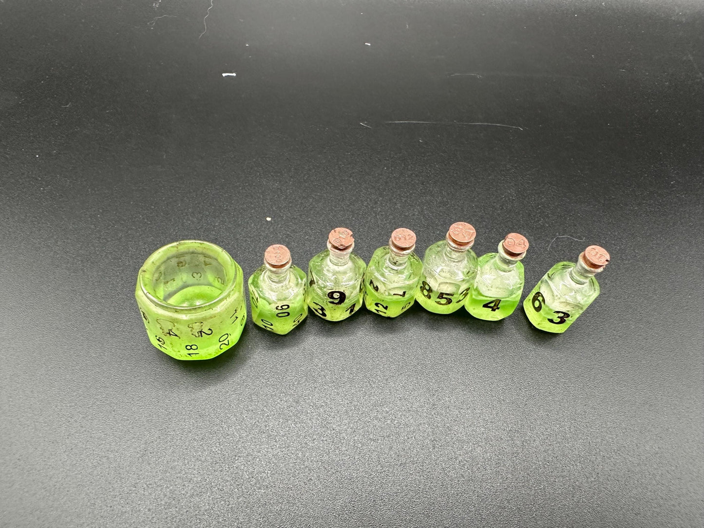 Green UV reactive dice set glowing like a witch’s potion; perfect for DnD, tabletop RPGs, and magical dice collectors; polyhedral set in moody lighting.