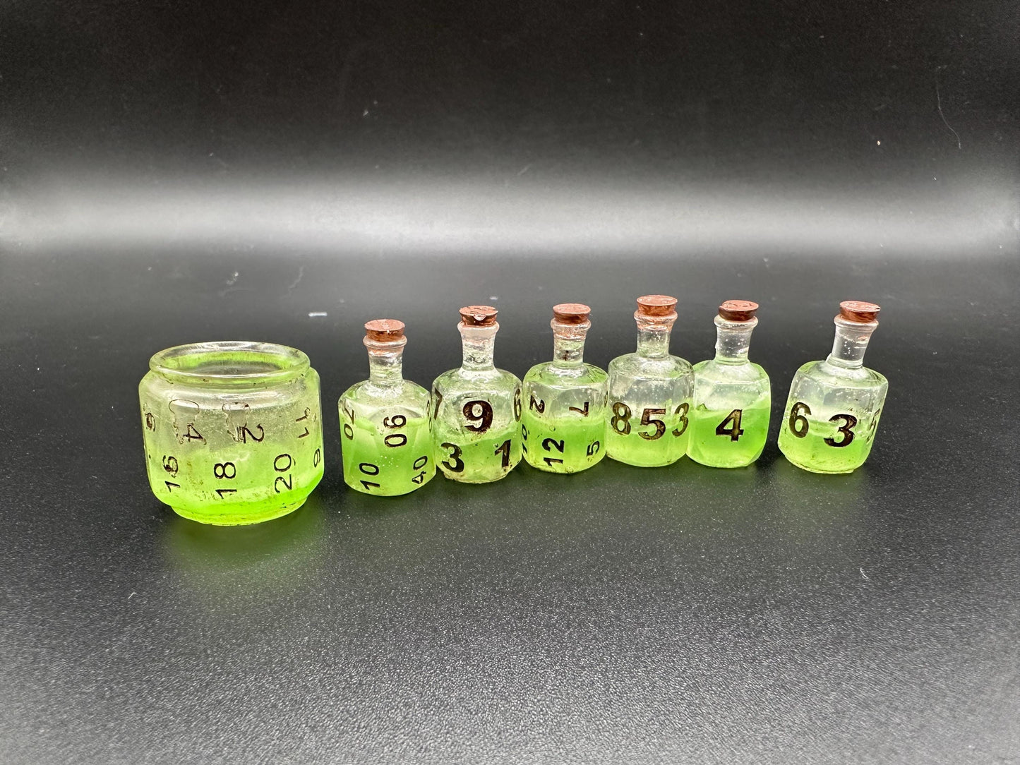 Green UV reactive dice set glowing like a witch’s potion; perfect for DnD, tabletop RPGs, and magical dice collectors; polyhedral set in moody lighting.