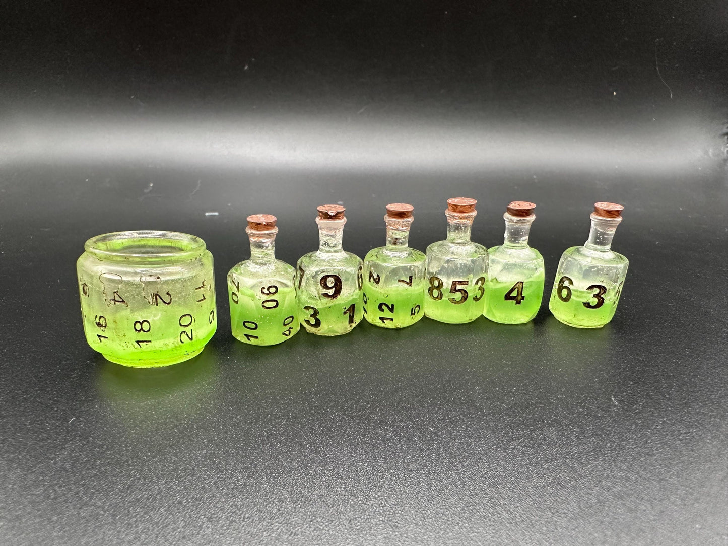 Green UV reactive dice set glowing like a witch’s potion; perfect for DnD, tabletop RPGs, and magical dice collectors; polyhedral set in moody lighting.