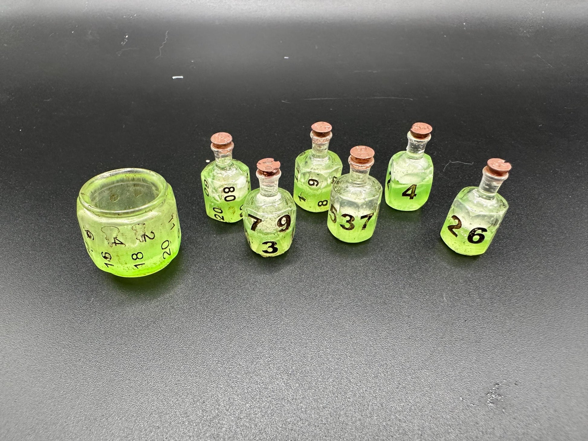 Green UV reactive dice set glowing like a witch’s potion; perfect for DnD, tabletop RPGs, and magical dice collectors; polyhedral set in moody lighting.