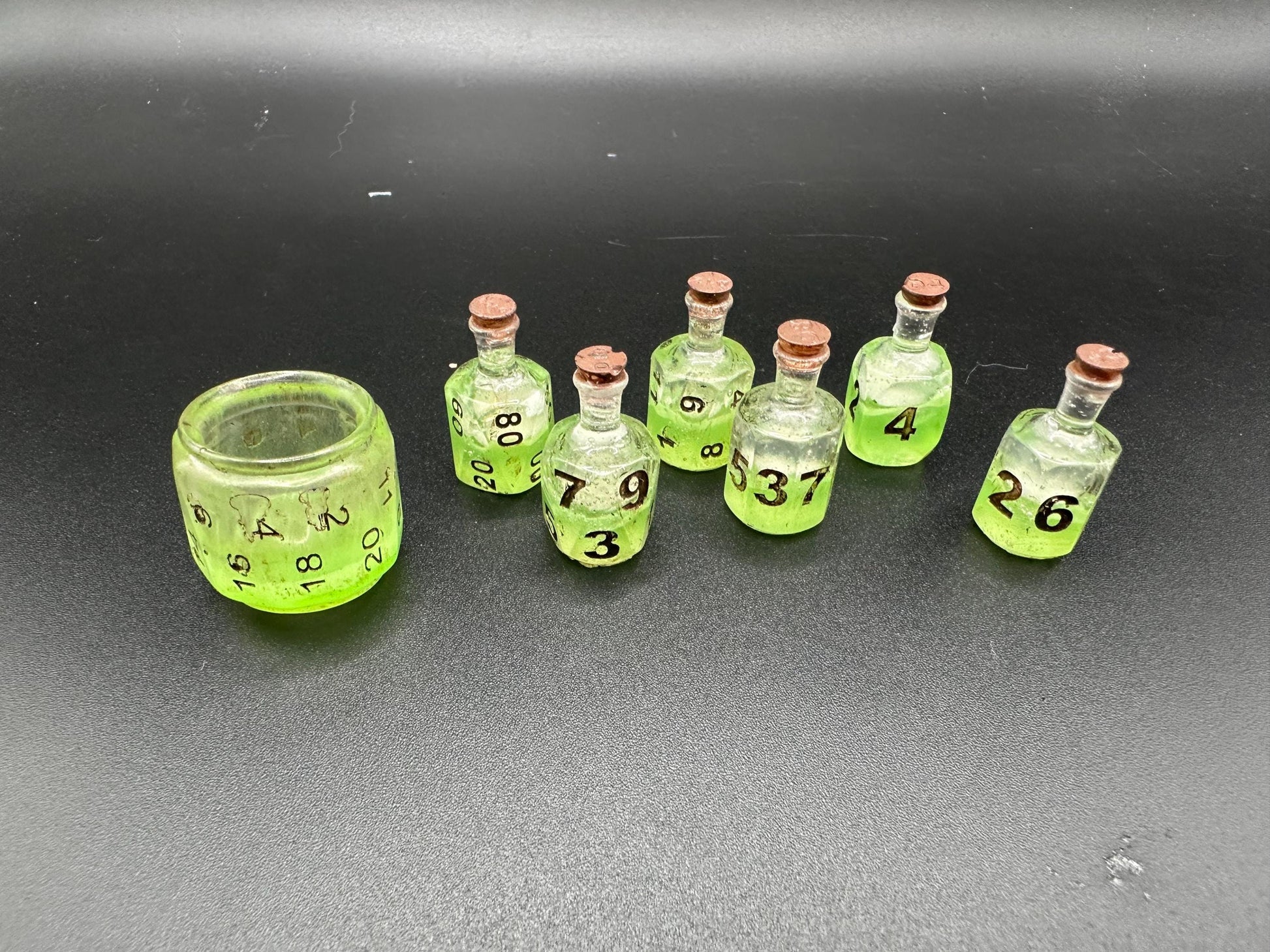 Green UV reactive dice set glowing like a witch’s potion; perfect for DnD, tabletop RPGs, and magical dice collectors; polyhedral set in moody lighting.