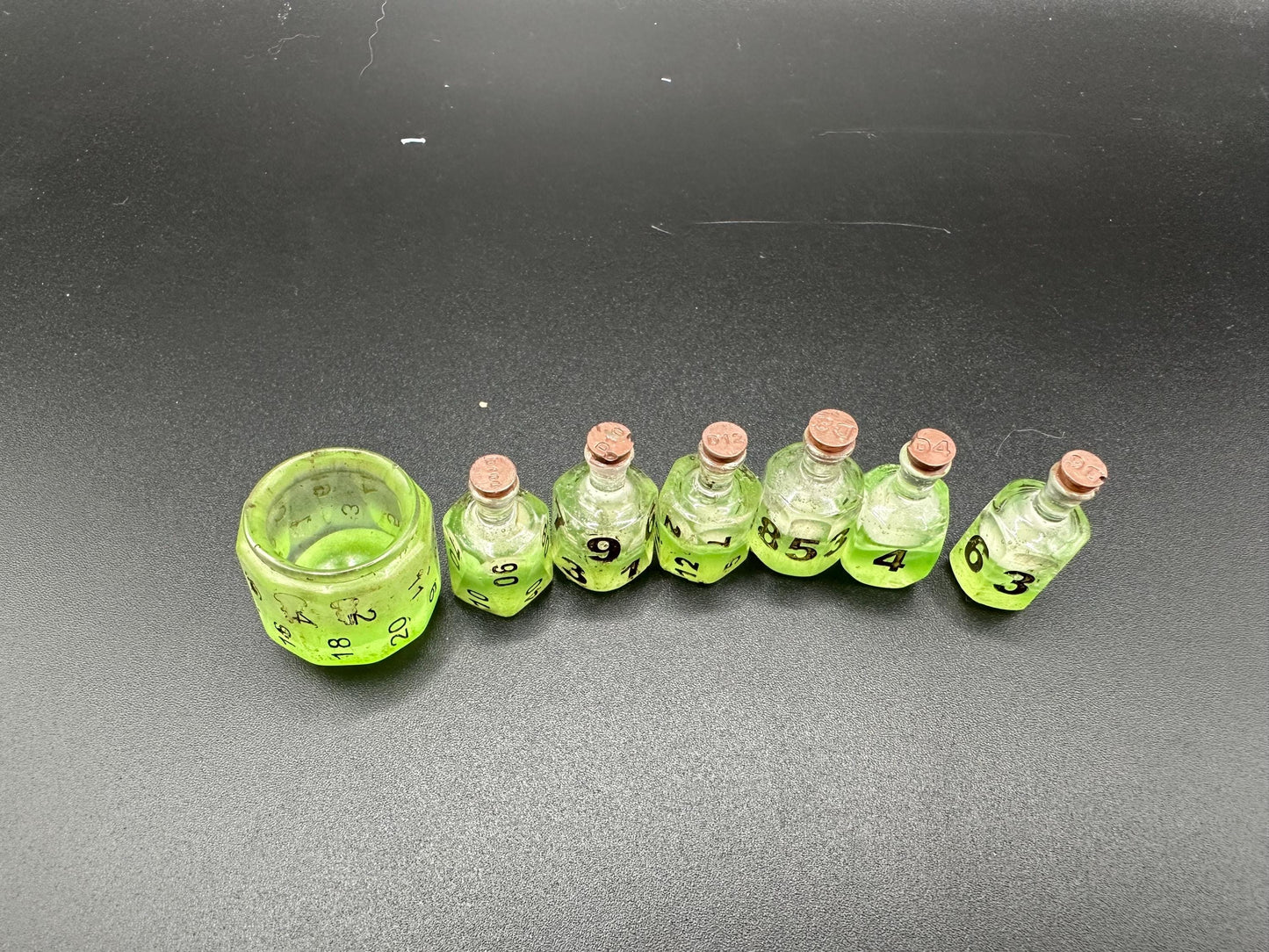 Green UV reactive dice set glowing like a witch’s potion; perfect for DnD, tabletop RPGs, and magical dice collectors; polyhedral set in moody lighting.
